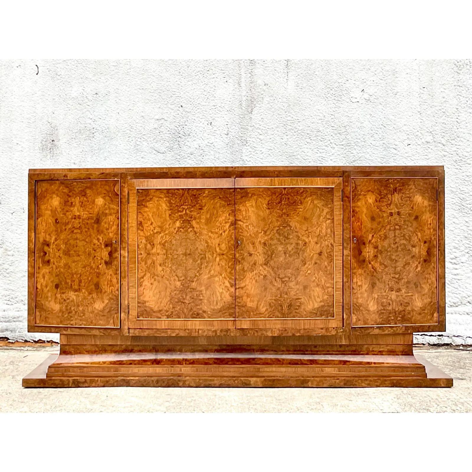 A fantastic vintage Art Deco credenza. A chic bow front cabinet that rests on a flared pedestal. Incredible book matched Burl wood. Spectacular wood grain detail. Acquired from a Palm Beach estate.