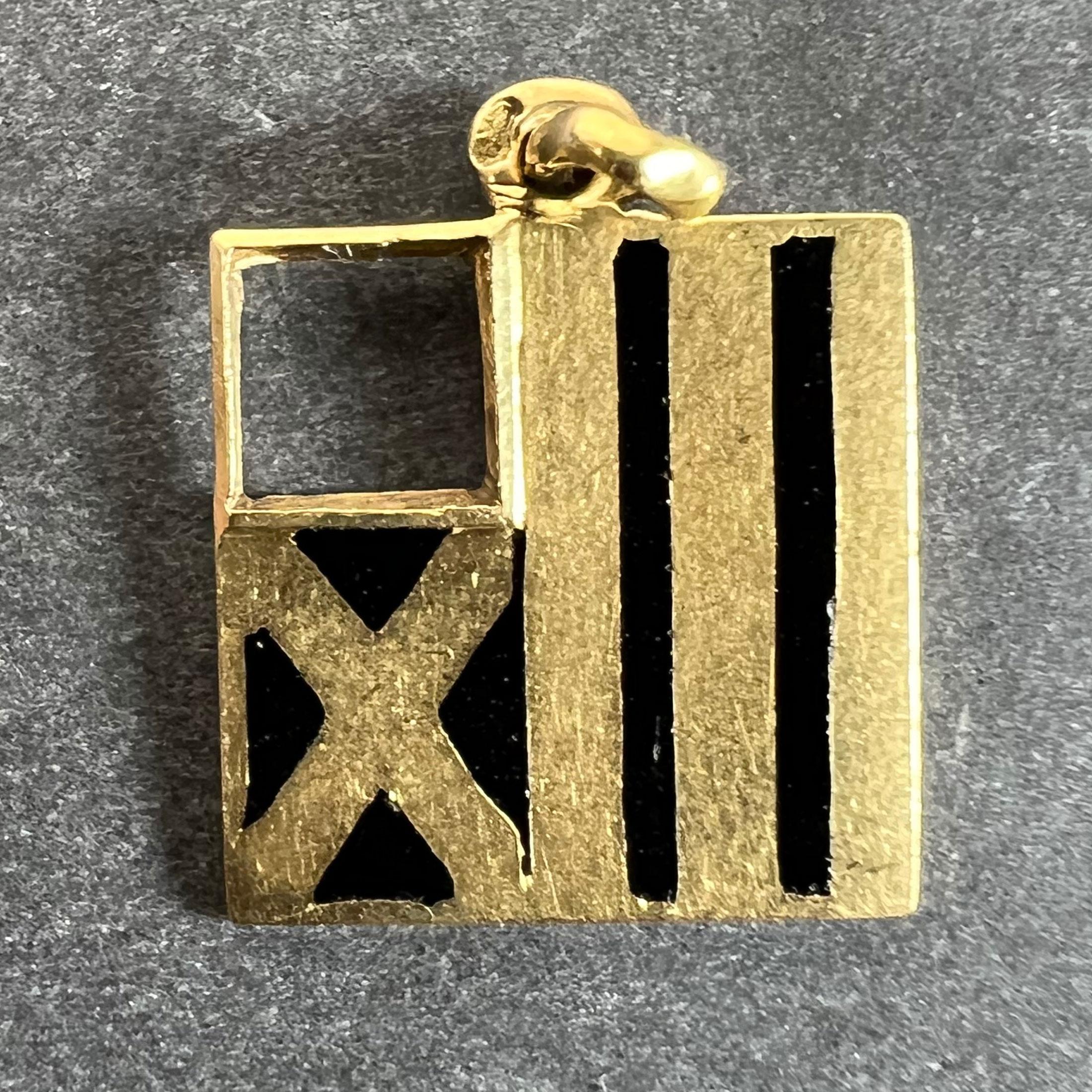 Pendentif breloque vintage en or jaune 18 carats (18K) serti d'émail noir conçu comme un drapeau avec une paire de bandes noires et une croix en or sur un fond noir. Le revers est gravé du symbole des Poissons, 