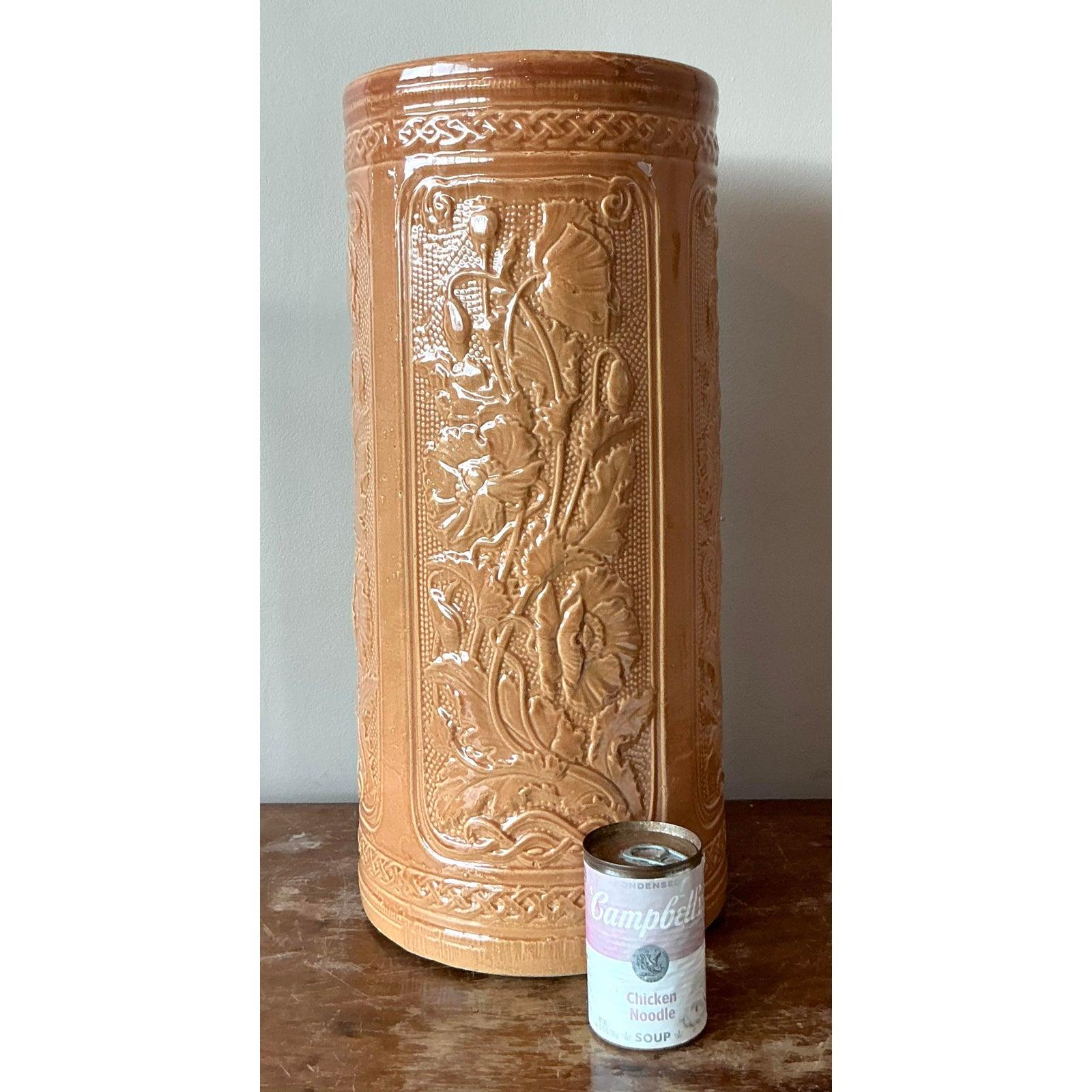 This charming vintage umbrella stand, crafted from glazed ceramic, features an exquisite embossed design of poppies, beautifully encapsulating the elegant aesthetics of the Art Deco era. The rich, earthy tone of the ceramic complements the detailed