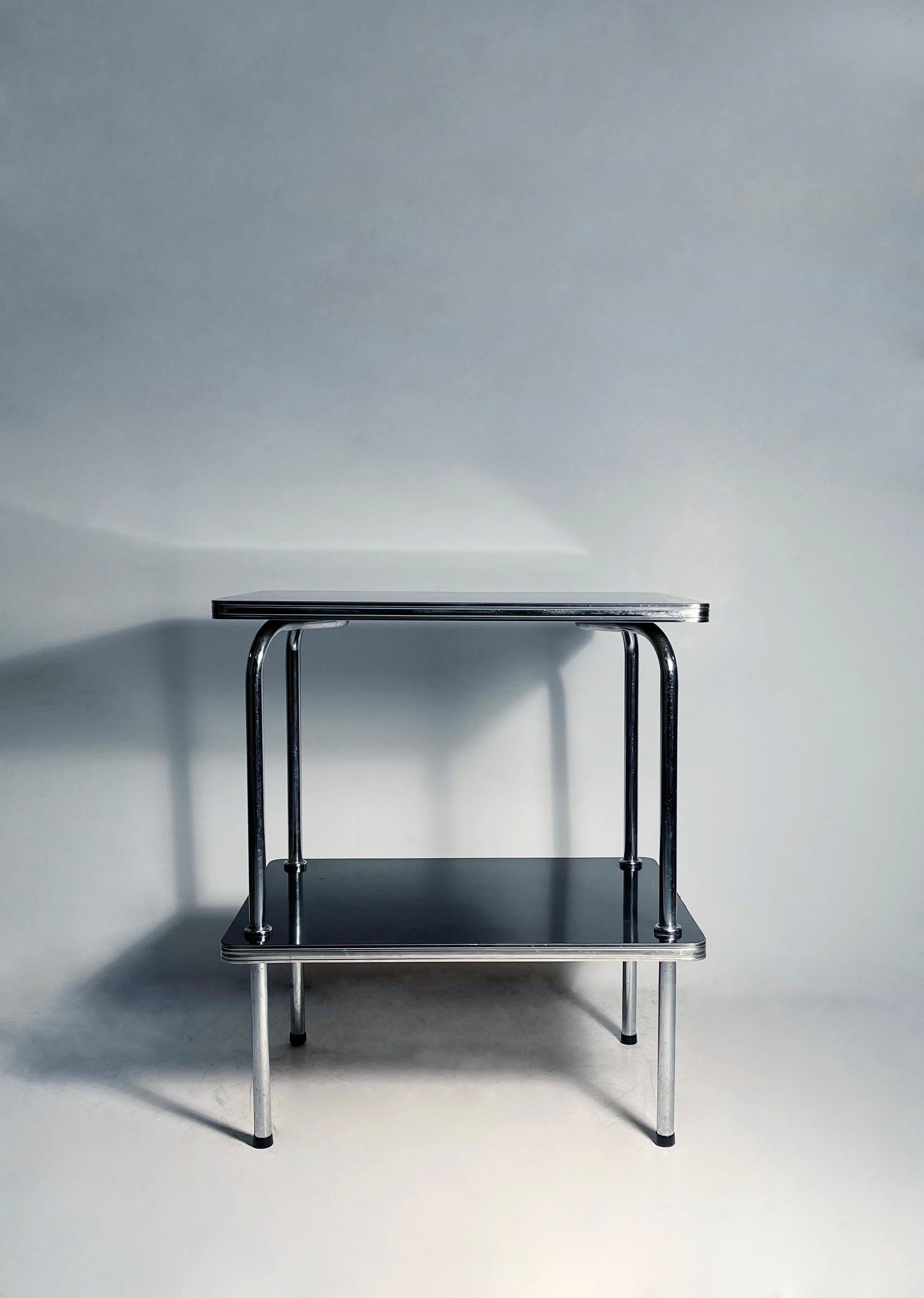 Hübscher, verchromter Beistelltisch im Vintage-Dekostil, entweder von Troy Sunshade oder Royal Chrome. Möglicherweise ein Gilbert Rohde oder in der Art von. 

leichte Gebrauchsspuren auf dem schwarzen Laminat,  Bitte fordern Sie weitere Fotos an.