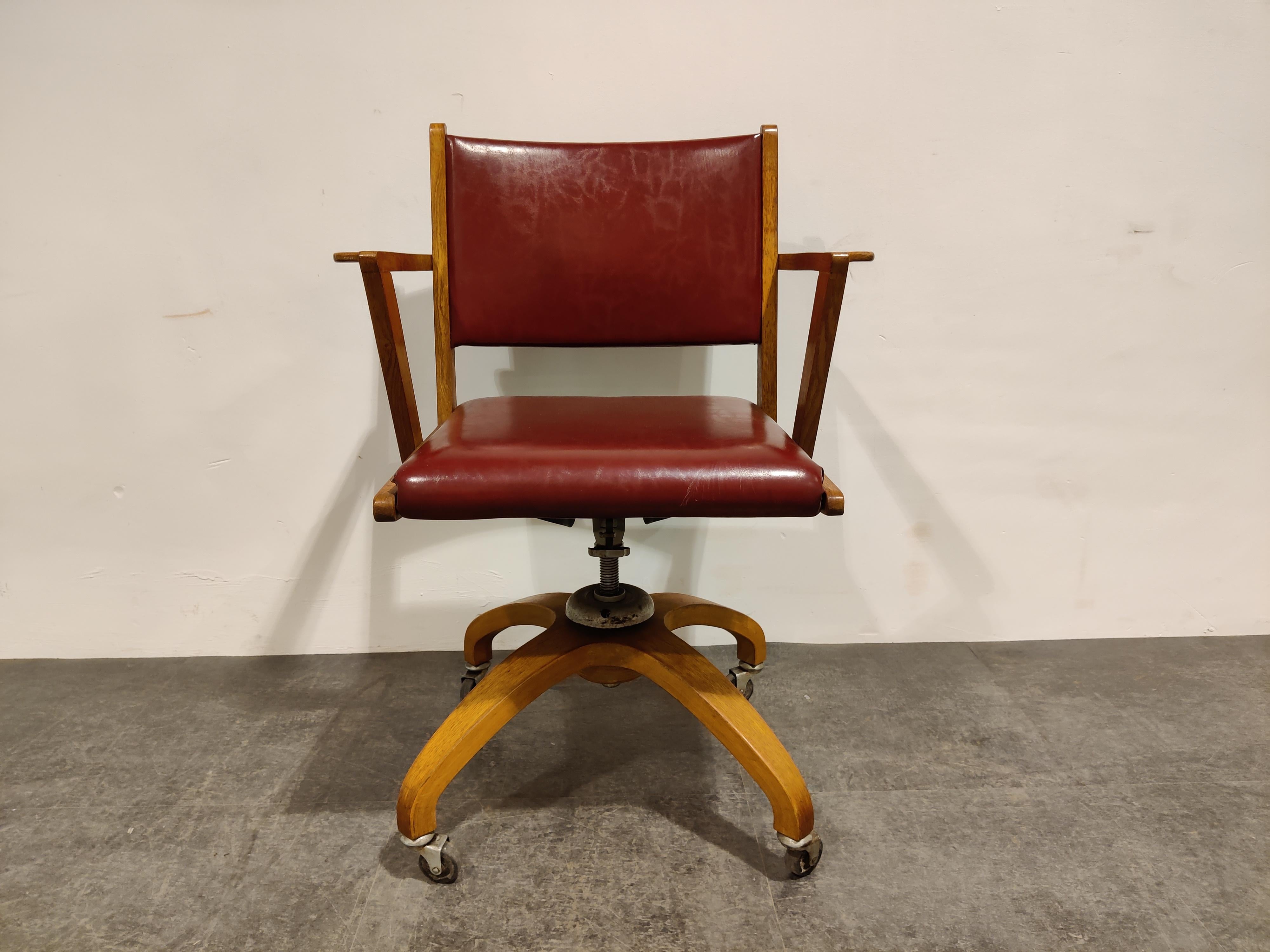 Original mid century desk chair by De Coene, made in Belgium.

Very good qualitative desk chair with a reclining function.

The chair is also adjustable in height by turning it.

Very good condition with dark red leatherette