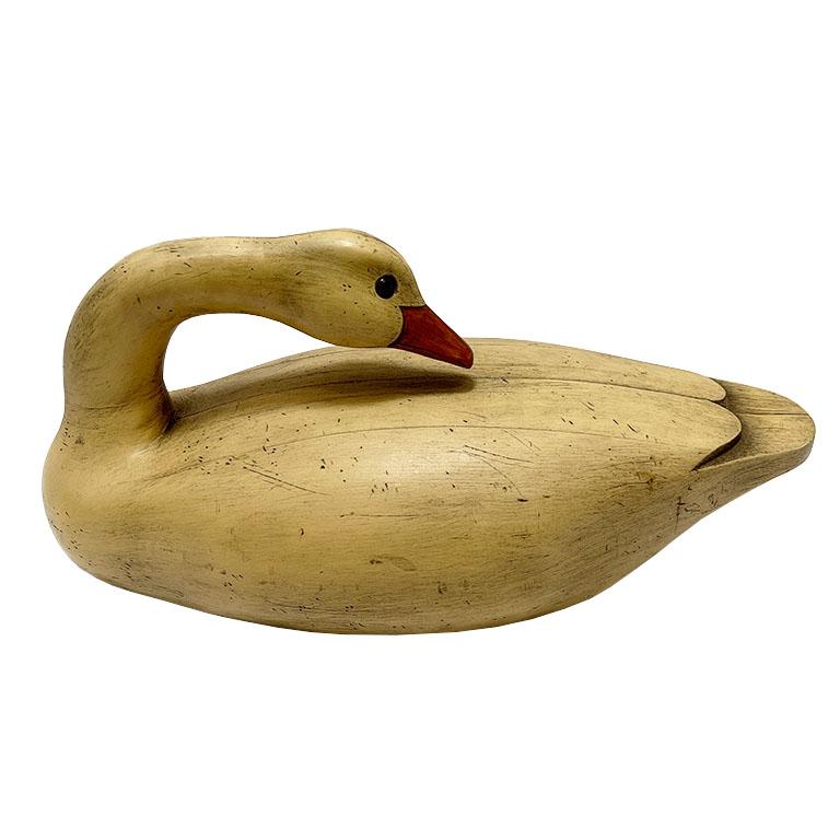 A large duck decoy in cream. This large bird decoy could resemble a goose, swan, or duck. (We aren't experts, unfortunately) It feels like wood, but we believe it is composite as it is hollow inside. The bottom is affixed to a piece of felt to