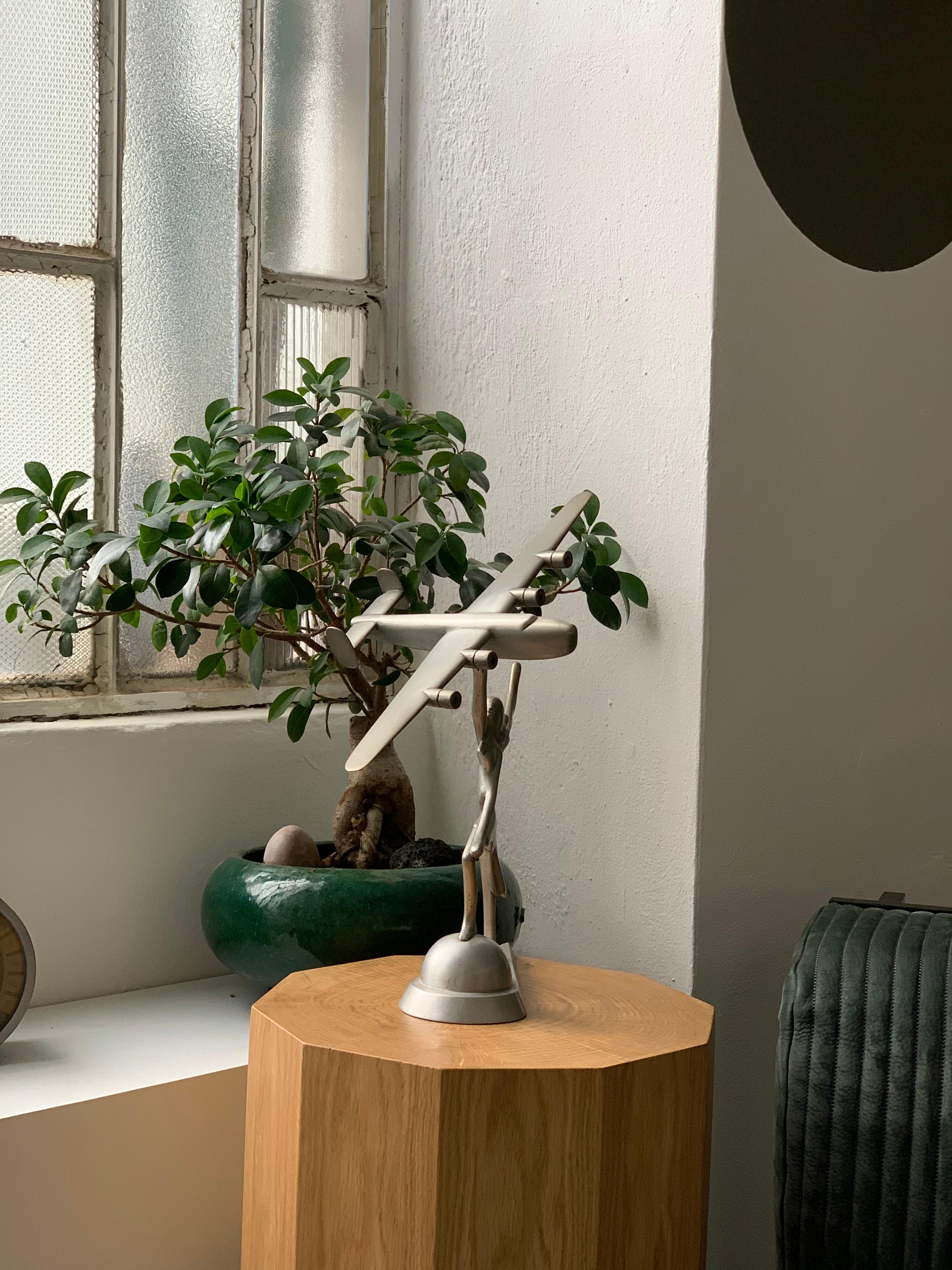 Coming from the house of an Italian WW2 Veteran, the present object is a decorative desk sculpture representing a goddess, possibly Minerva, holding in her hand a faithful reproduction of a Consolidated B-24 