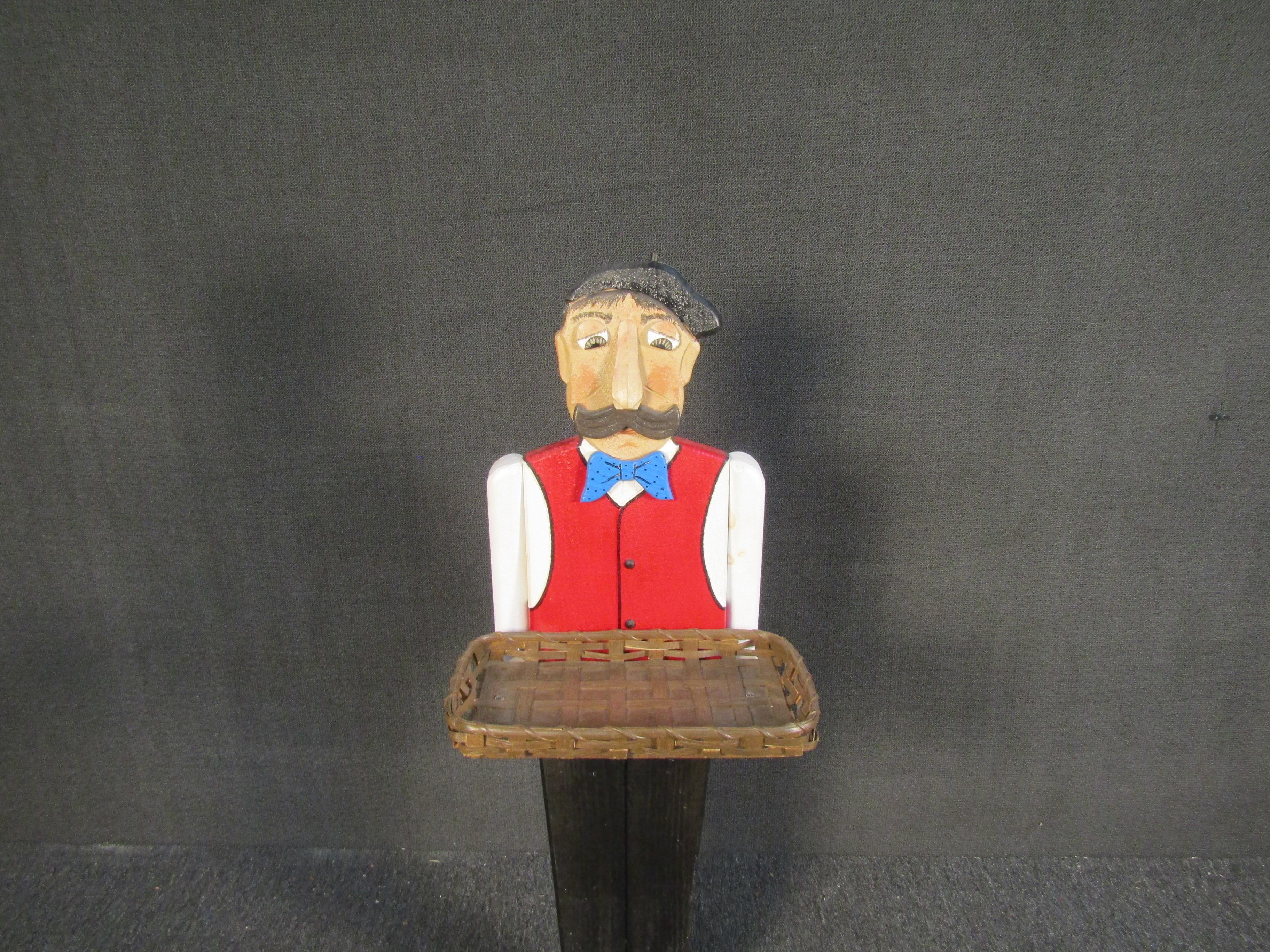 This vintage decorative sculpture depicts a waiter and includes a wicker serving tray for placing items on. Unusual and unique, this vintage piece can add decorative flair to a kitchen or dining room. Please confirm item location with seller (NY/NJ).