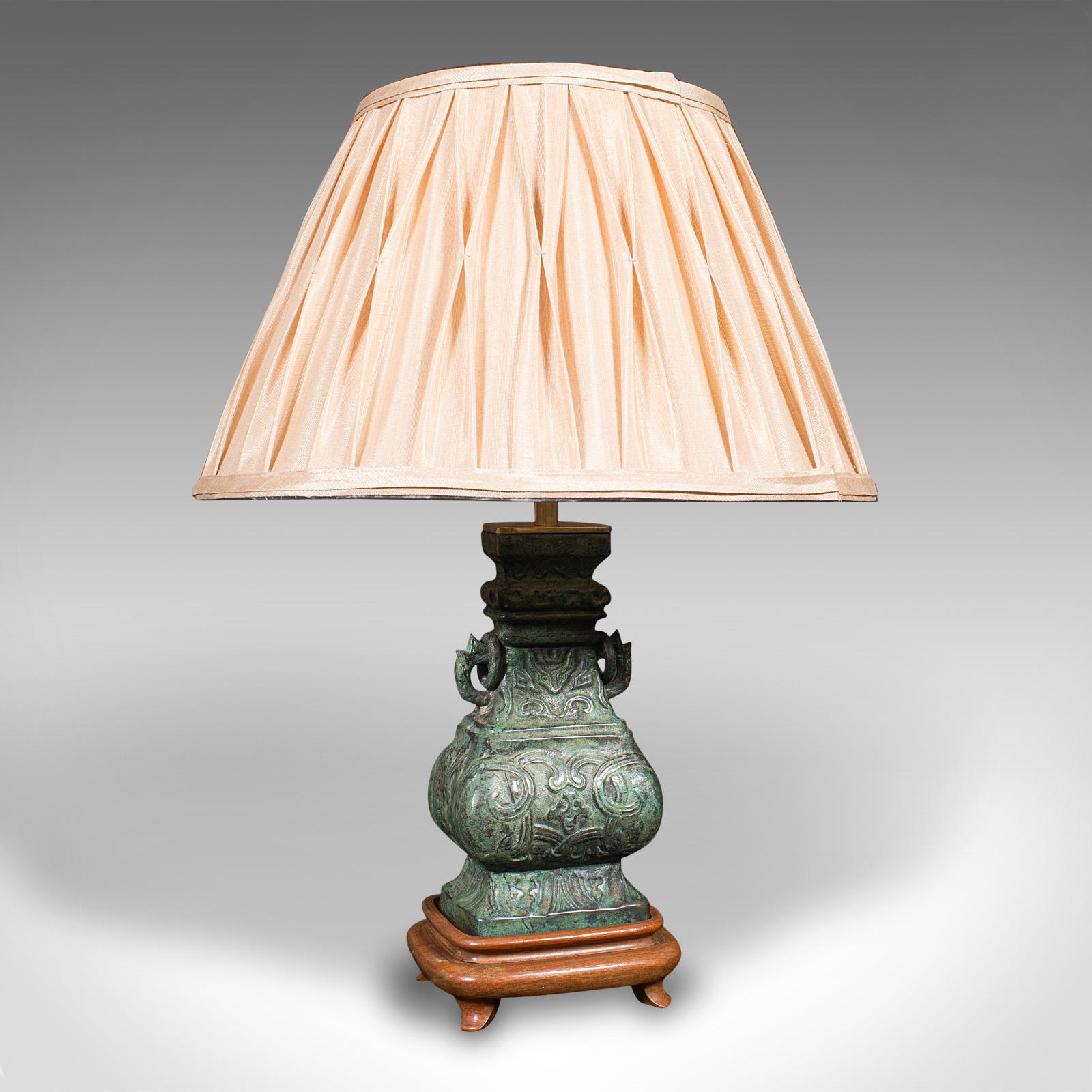 This is a vintage decorative table lamp. A Chinese, bronze over mahogany accent light, dating to the mid 20th century, circa 1960.

Of appealing finish and proportion, ideal for the side table
Displays a desirable aged patina throughout
Bronze