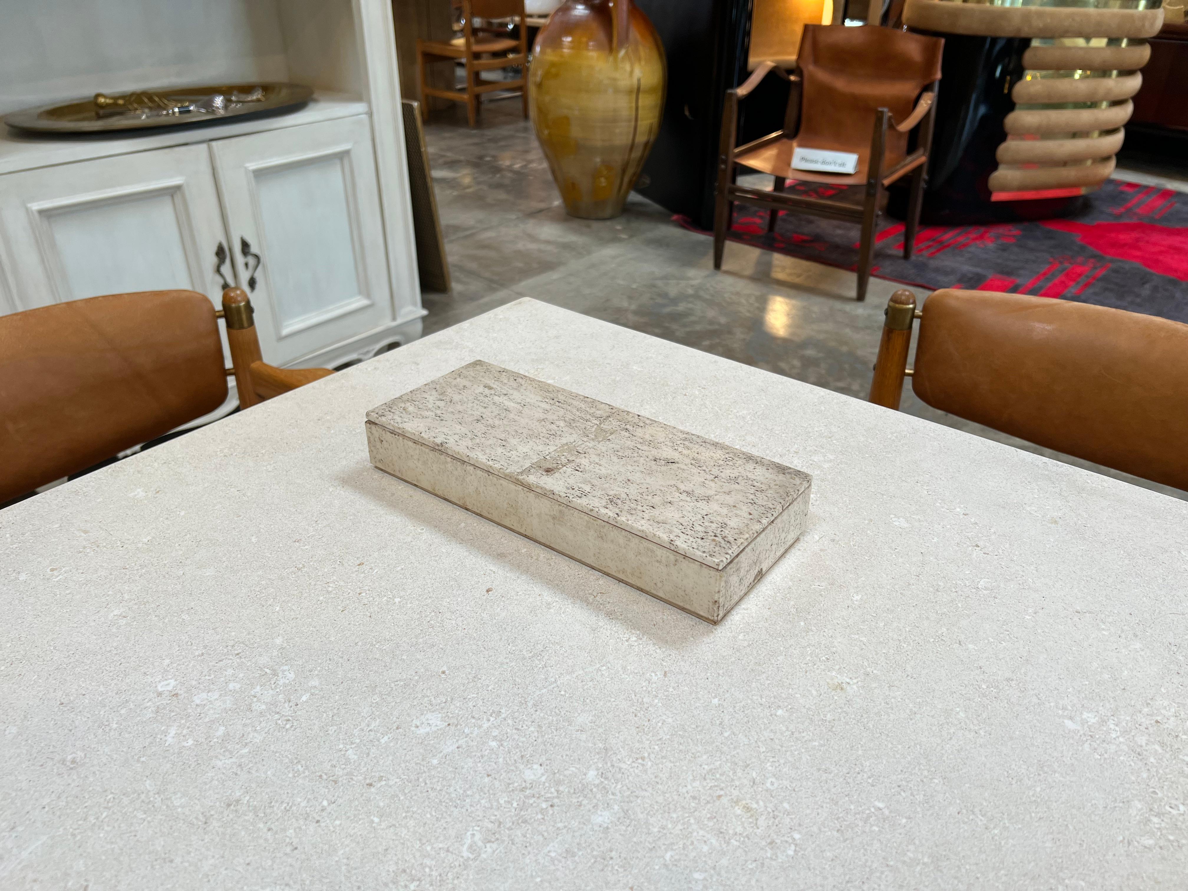 The Vintage Decorative Travertine Box from the 1980s is a meticulously crafted box entirely fashioned from travertine stone. Dating back to the 1980s, this unique piece showcases the beauty of natural stone, featuring intricate patterns and