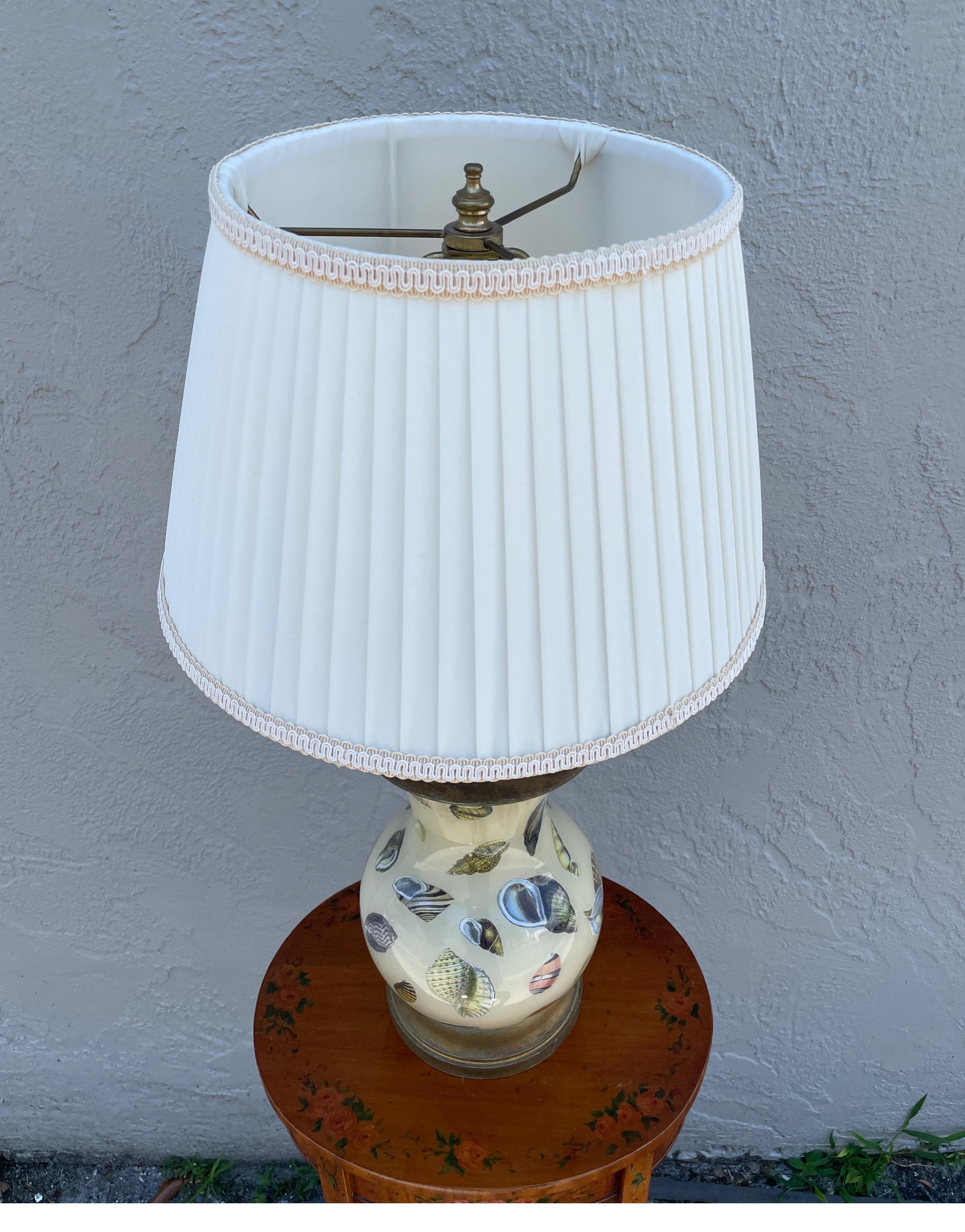 Vintage decoupage lamp with a variety of shell images on a cream colored background.