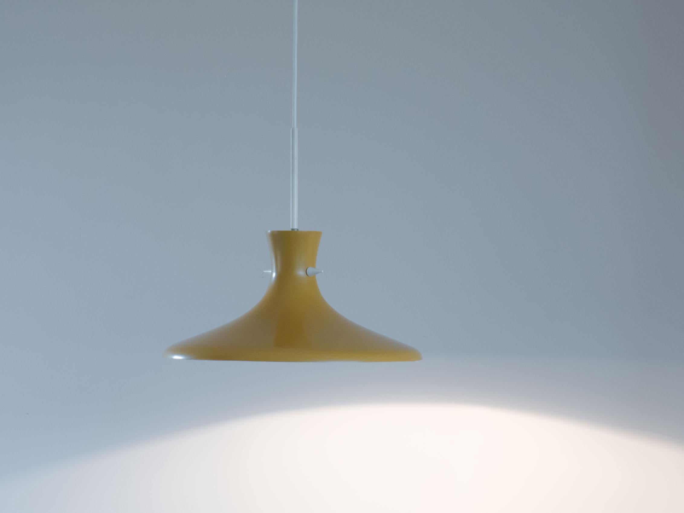 Organisch geformte, ockergelbe Vintage-Hängelampe.

Diese Lampe ist sehr minimalistisch gestaltet, der Schirm hat zwei kleine weiße Spitzen, die die Form des Schirms betonen.

Diese Lampe ist in sehr gutem Zustand. Der Schirm hat altersgemäße