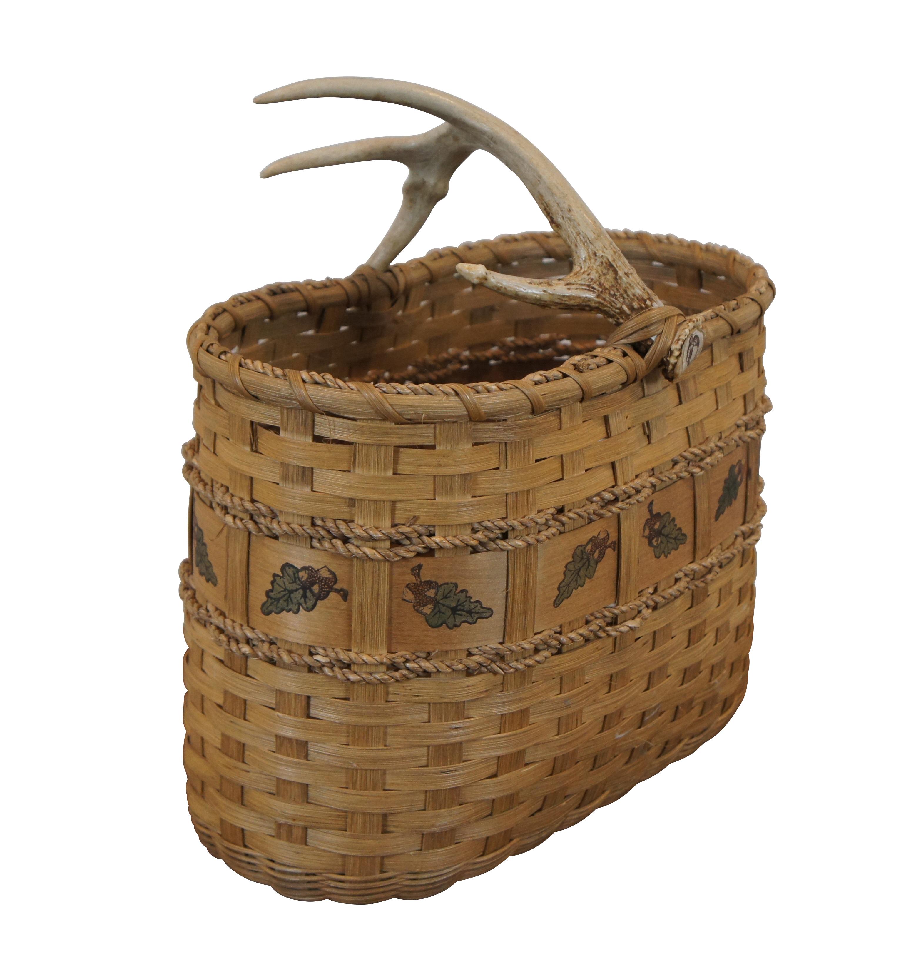 Large vintage wicker harvest basket featuring antler handle with acorn / leaf theme and rope twist accents.

Dimensions:
16” x 9.5” x 17” (Width x Depth x Height)
