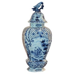 Urne vintage en Delft avec scène figurative et fleuron en forme d'oiseau