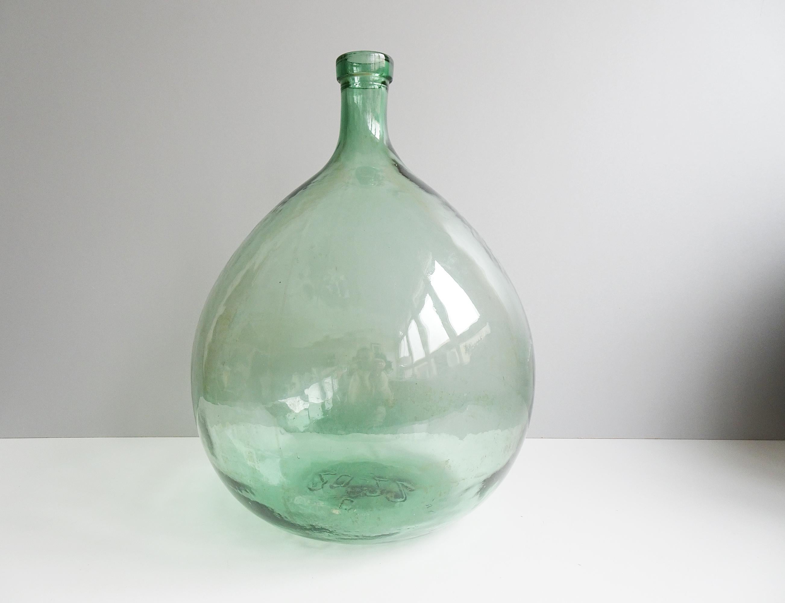 Large imposing glass balloon in light green. A great timeless home accessory that is ideal as a floor vase for dried flowers and is a great light catcher. Due to its size and the good condition, the bottle is very decorative and a great eye-catcher