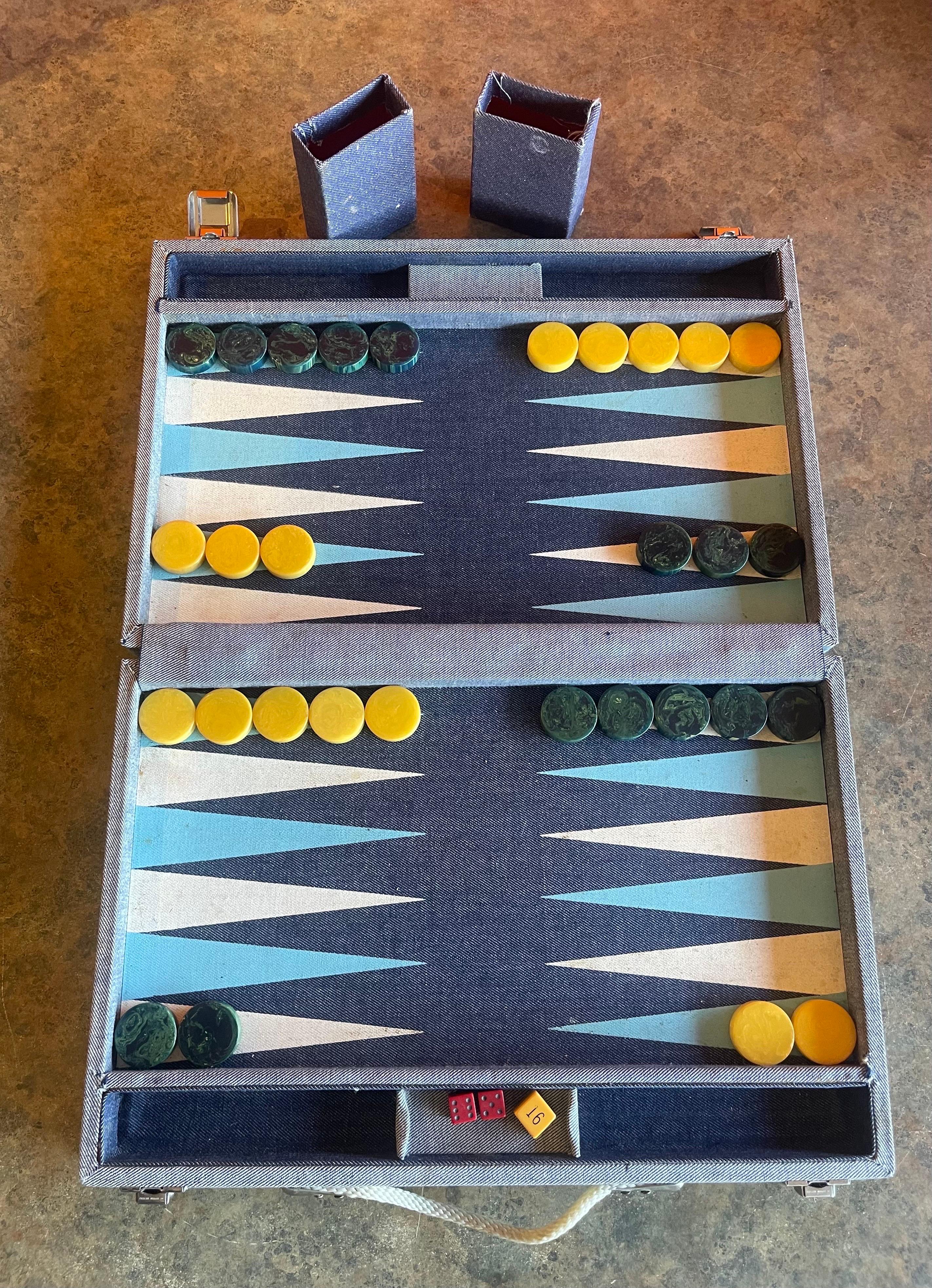 Vintage denim & bakelite backgammon set, circa 1950s. Set is complete with a foldable case / board with denim fabric, 30 bakelite checkers (bright yellow and deep blue in color), doubling cube, two dice cups and a pair of vintage dice. Overall, the
