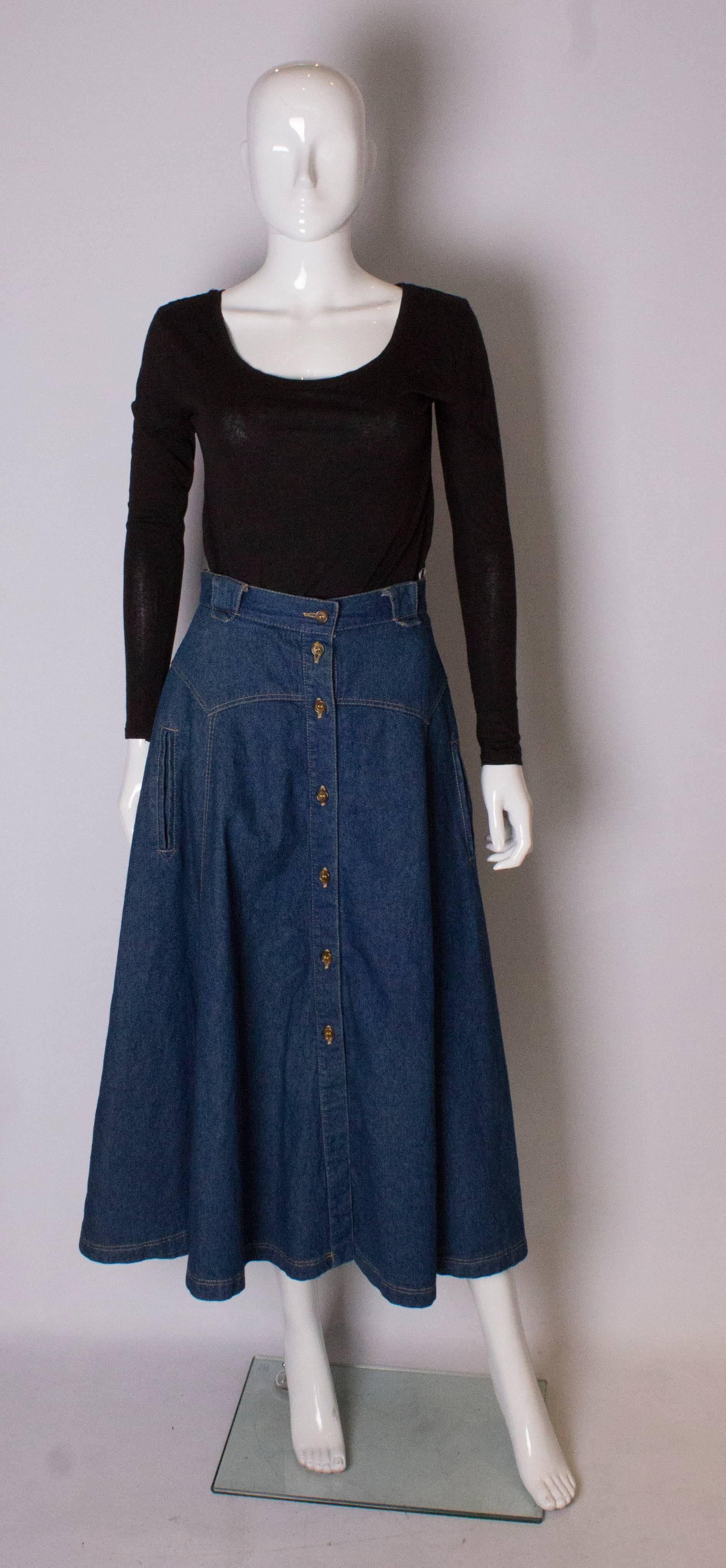 A great denim skirt from the 1970s. The skirt is panelled with decorative pockets on the front, belt hoops and a button through opening.