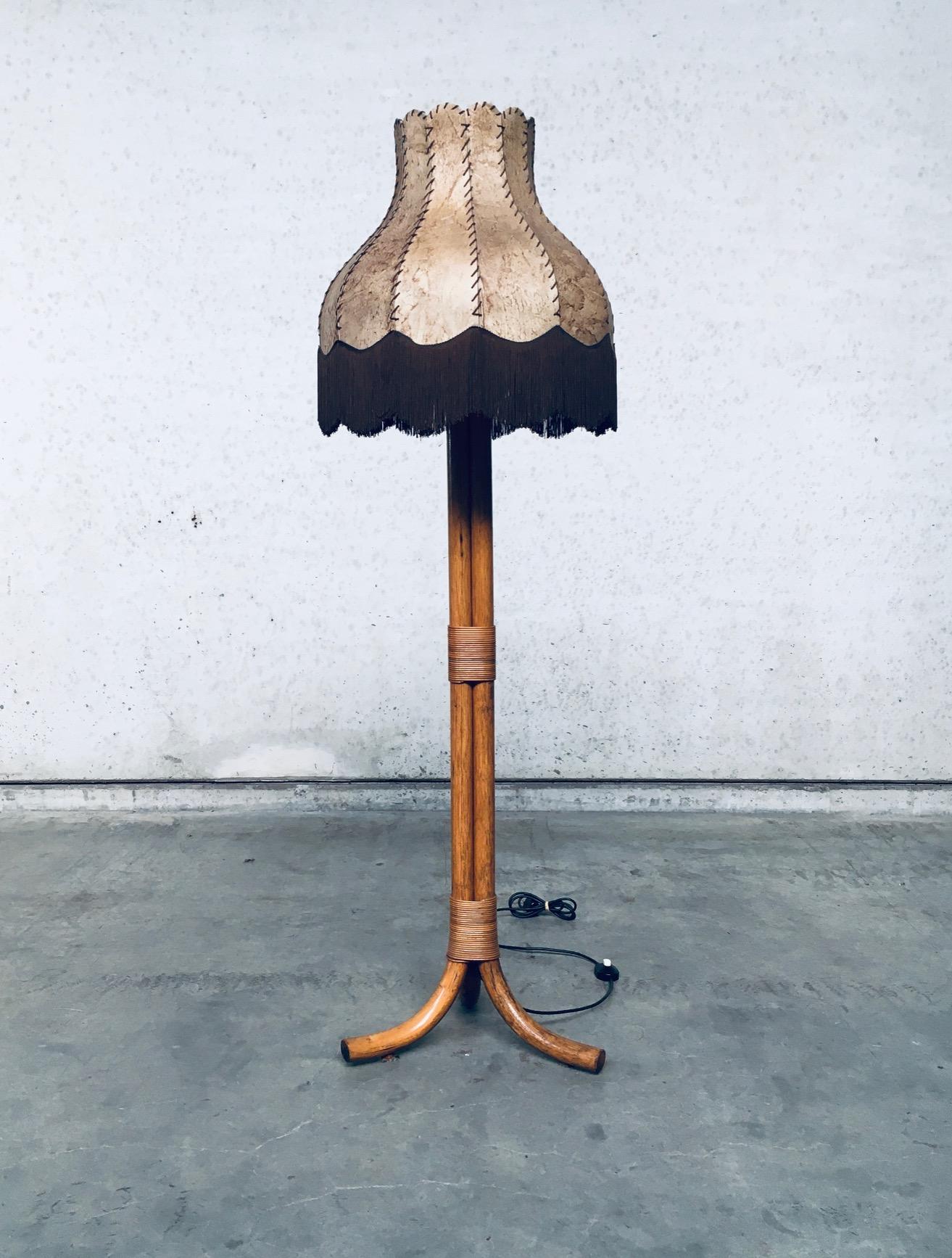 Vintage midcentury design bamboo floor lamp with leather lampshade, made in Italy 1970's. 3 Bamboo bound foot with leather stretched with fringe lampshade. In very good, original condition. Measures in total 50cm x 170cm x 50cm.