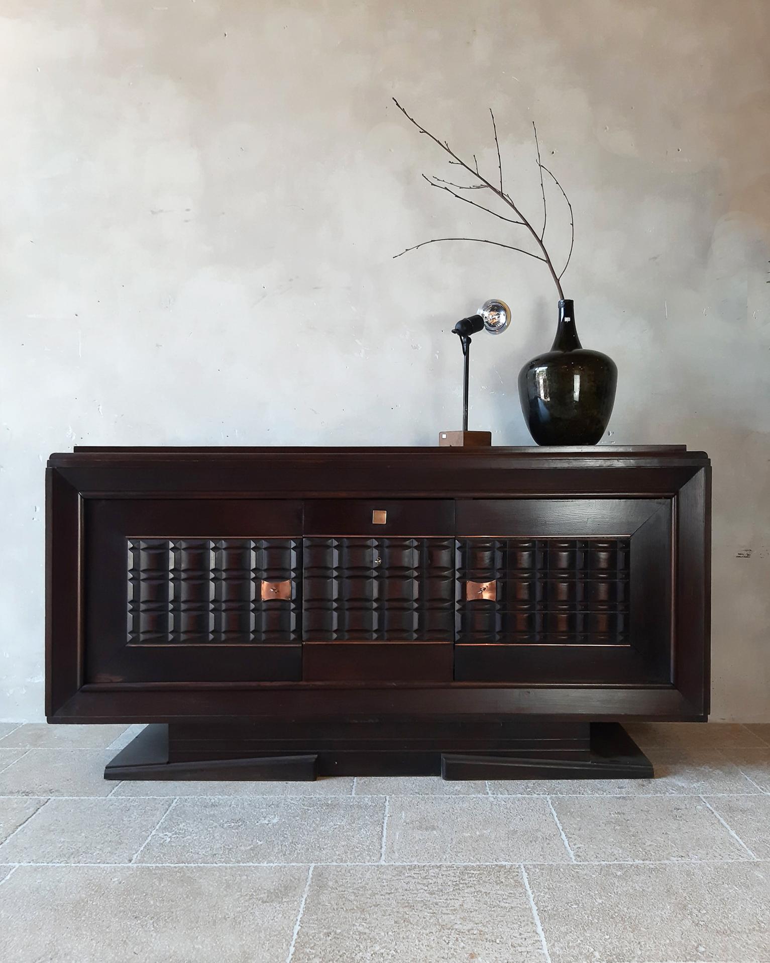 Vintage design sideboard by Charles Dudouyt in dark oak, 1940s-50s. The doors of this beautiful credenza are cut out in graphic and geometric shapes. With copper-coloured details.

Dimensions: H 100 x W 200 x D 54 cm.