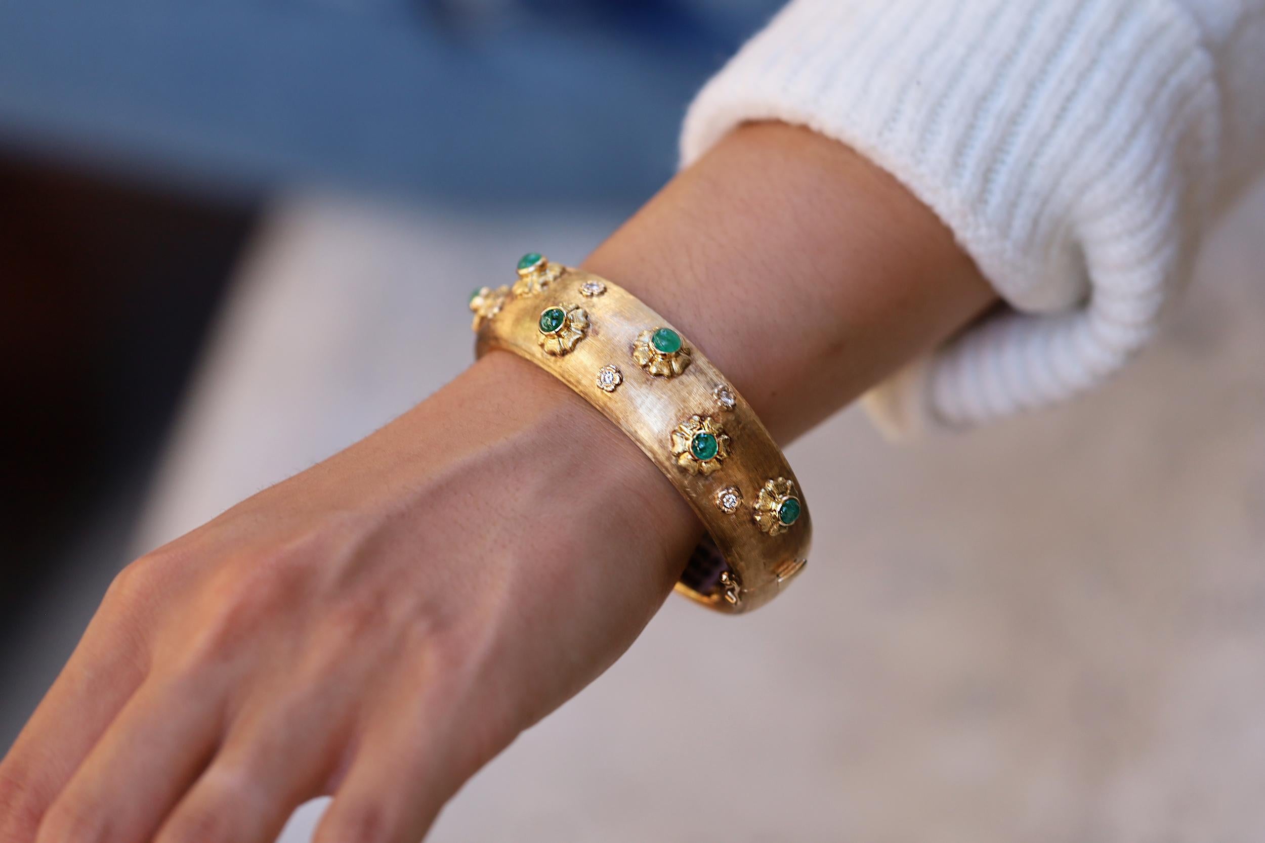 This highly unusual vintage 1960s bangle bracelet bursts with lush emerald cabochon gems. Its sparkling diamond accents bring a touch of luxe to the asymmetrical cuff. Expertly crafted in 14k gold with a brushed, Florentine finish, the bracelet's