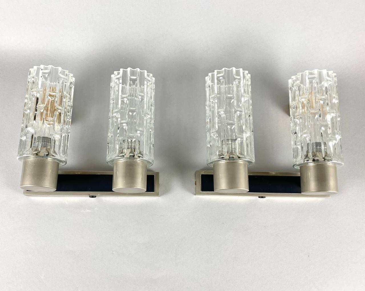 Beautiful set of two wall lights by Hillebrand, Germany.

A fine set of 2 Hillebrand metal and glass wall lamps in Mid-Century Modern style. 

The textured cylindrical glass shades mounted to a metal base.

Hillebrand brings German design and