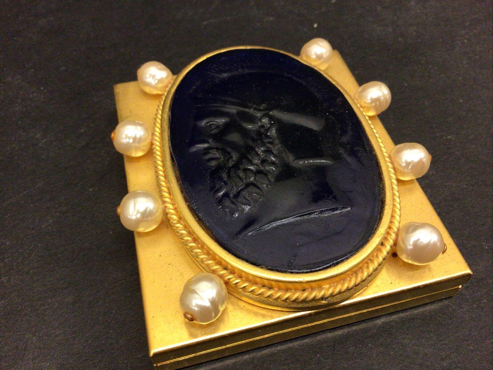 Compatto d'oro opaco vintage firmato dalla designer Linda Levinson, con al centro un medaglione di monete in vetro romano e circondato da perle. Interno a doppio specchio. Misura circa 2,75
