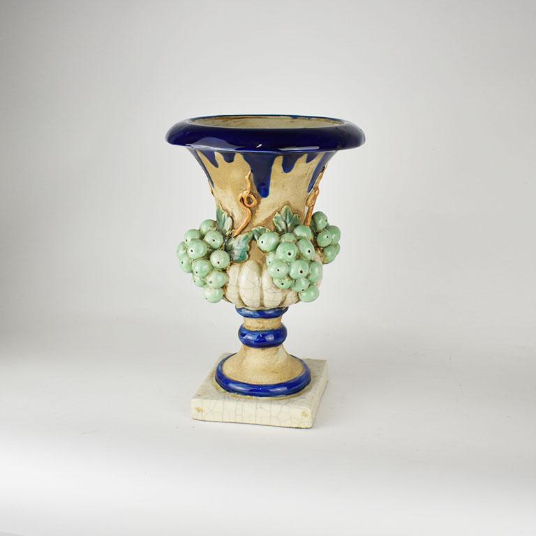 A fabulous vintage majolica planter or urn by Sarreid. Created in Italy, this piece has a very Tuscan feel. It is round and sits upon a square base. The body of the vase is highly decorated in green trompe L’Oeil grapes which protrude from the