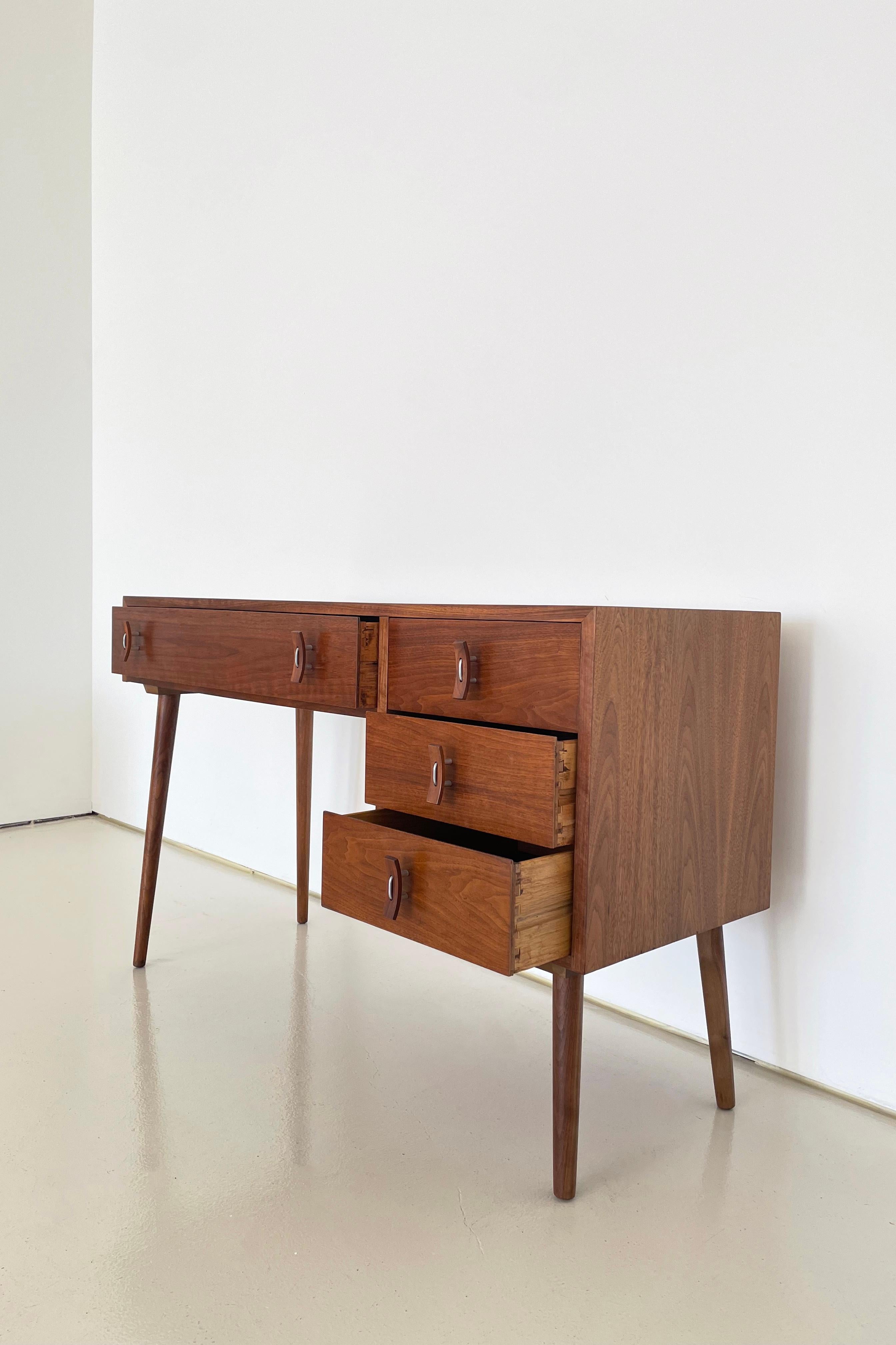 Manufactured in the US in the 1950’s

Solid Walnut legs with Walnut veneer drawer and case facades

Solid wood dovetail drawer construction with the original composite drawer bottoms. See photos.

This collectible desk is in the original finish and