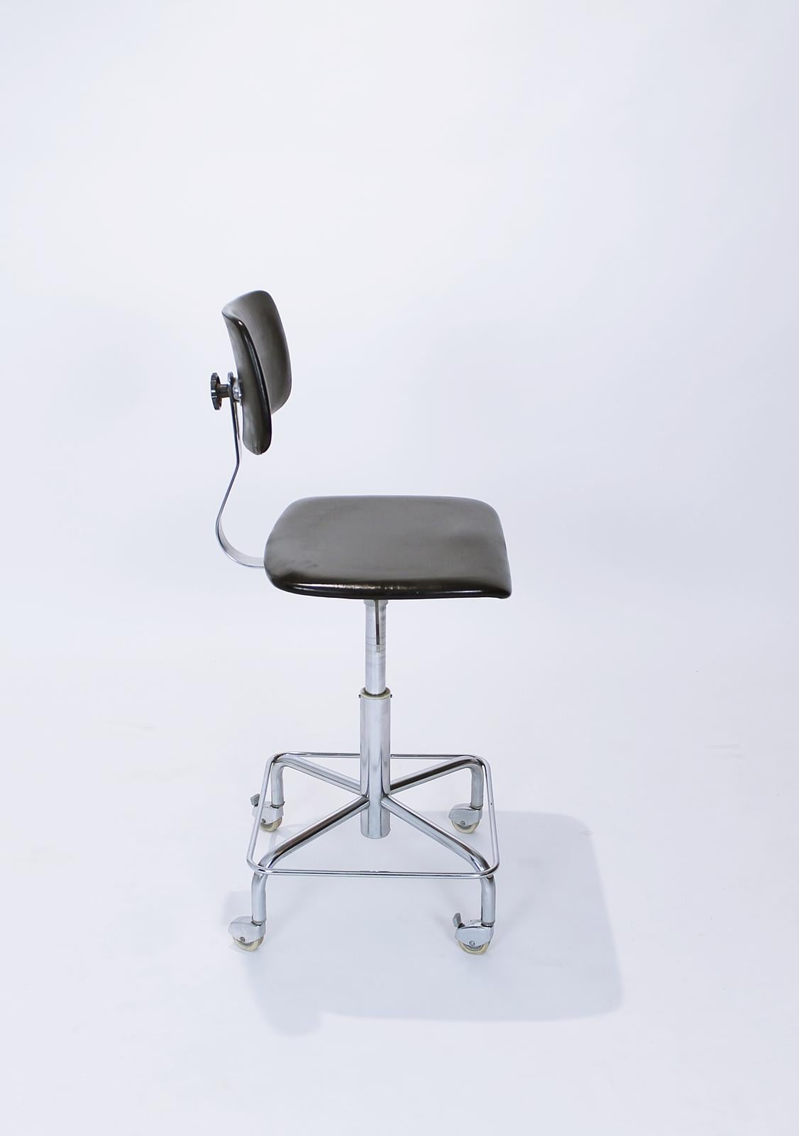 Vintage mid century rolling desk swivel chair by Bremshey, Germany.
This chair has a chromed steel frame, the back and seat are black vinyl.
The chair is height adjustable with gas spring.
The chromed metal frame has four wheels with Haco parking