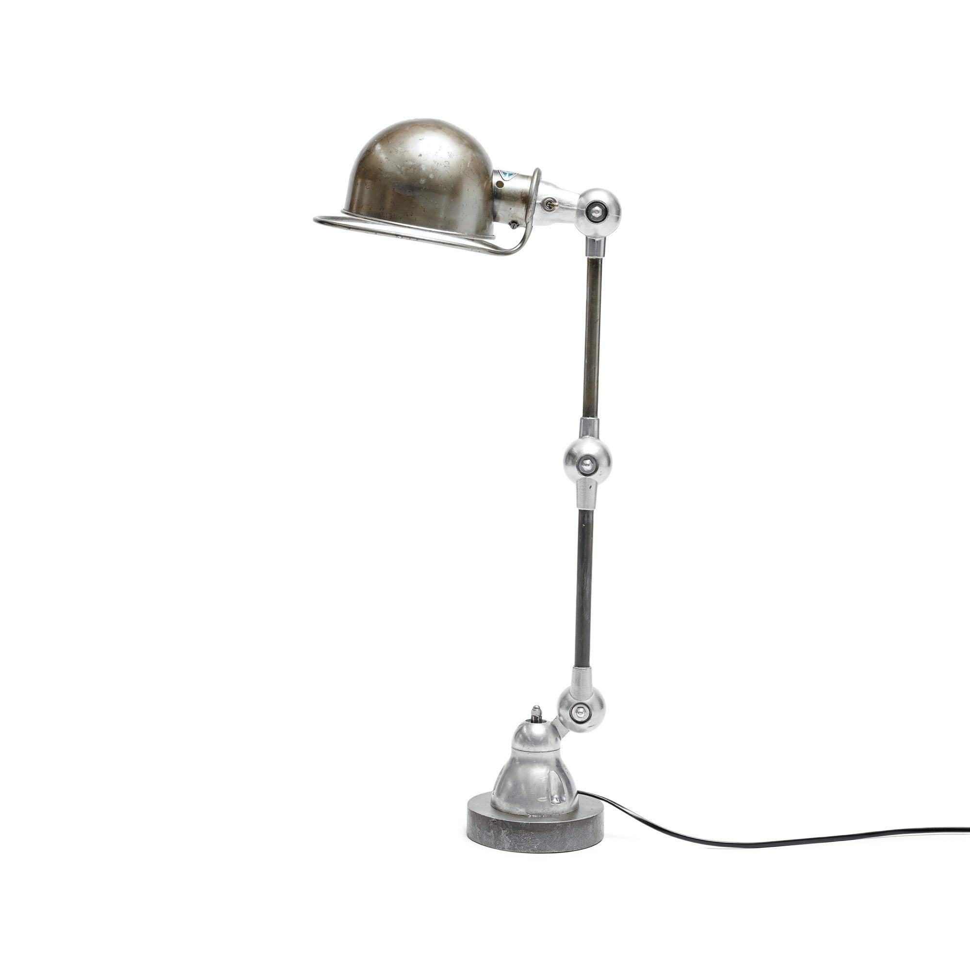 The Jielde desk lamp has two arms and three joints, and it's attached to a sturdy steel base. It was created in the 1950s by a French engineer named Jean-Louis Domecq for use in factories as a versatile work lamp that can be adjusted in various
