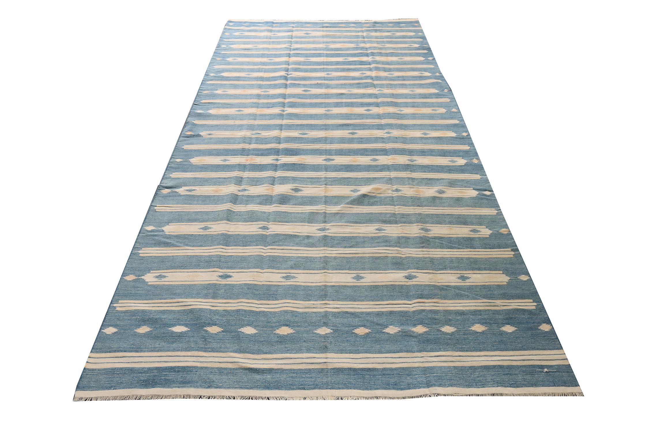 This vintage 5×11 Dhurrie is an exciting new entry in Rug & Kilim’s esteemed flat weave collection. Handwoven in cotton, it originates from India circa 1950-1960. 

On the Design:

This flat weave unfurls in blue and off-white stripes for a
