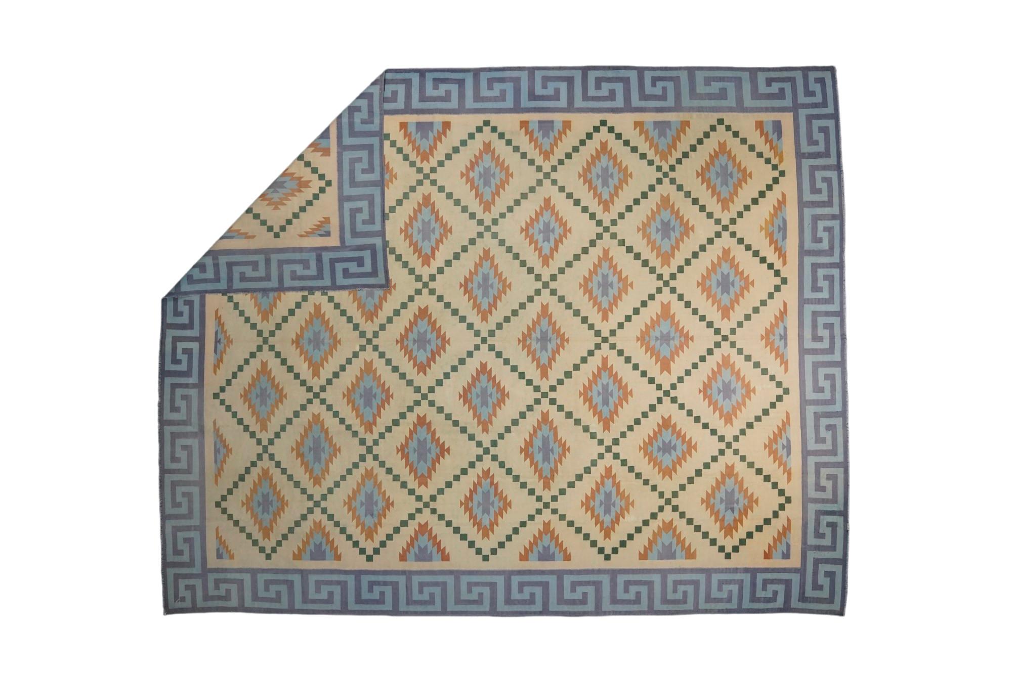 Ce tapis 10x13 est un rare tapis Dhurrie vintage issu d'une nouvelle collection de Rug & Kilim. Tissé à la main dans un coton à armure plate, il provient de l'Inde vers 1950-1960, et présente des tons crème avec des motifs géométriques bleus. 

Sur