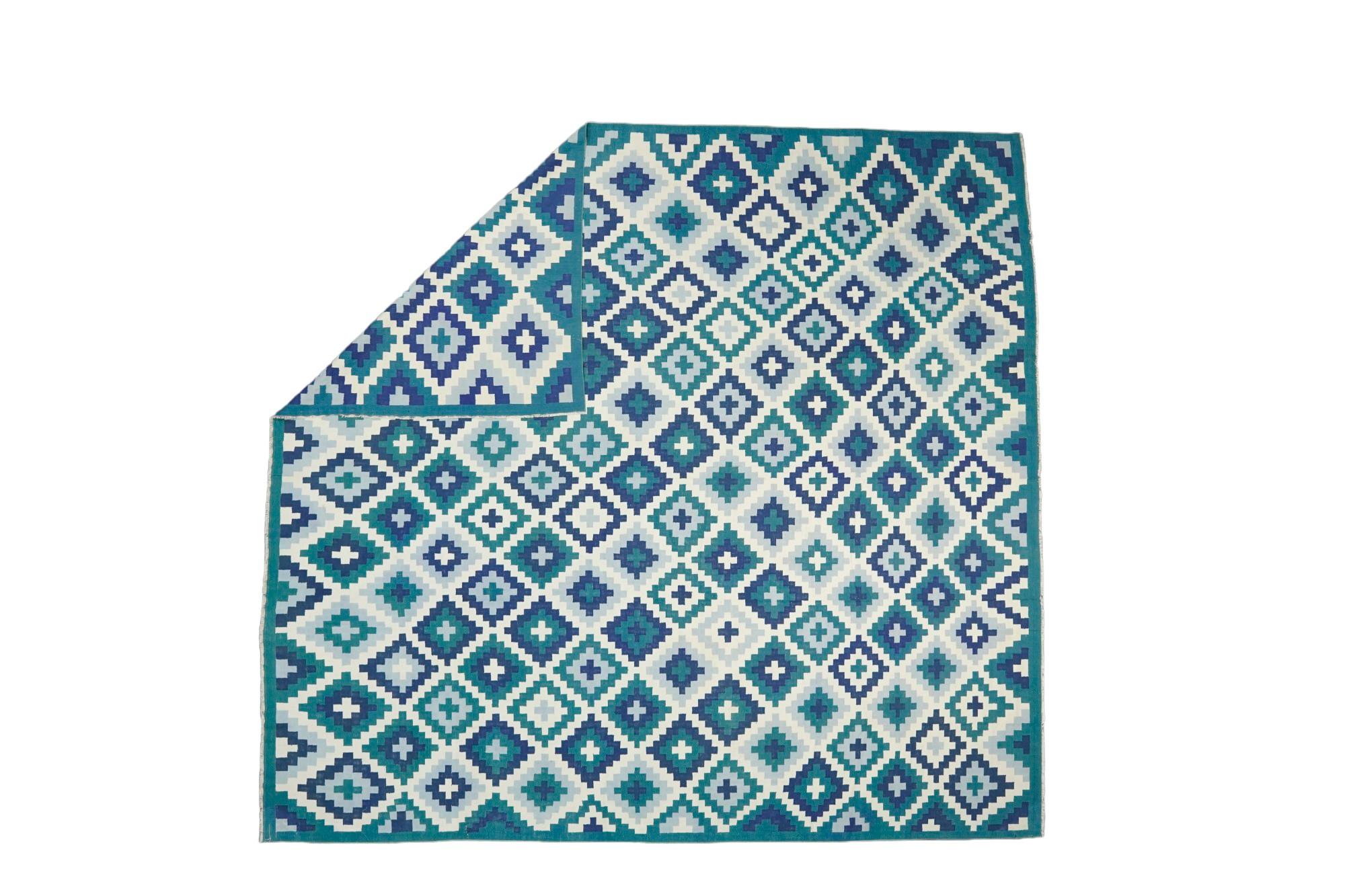 This 11x11 rug is a rare vintage Dhurrie rug from an exciting new mid-century curation by Rug & Kilim. Handwoven in a wool flatweave, it originates from India circa 1950-1960, and enjoys white and teal jewel tones in an all over geometric pattern.