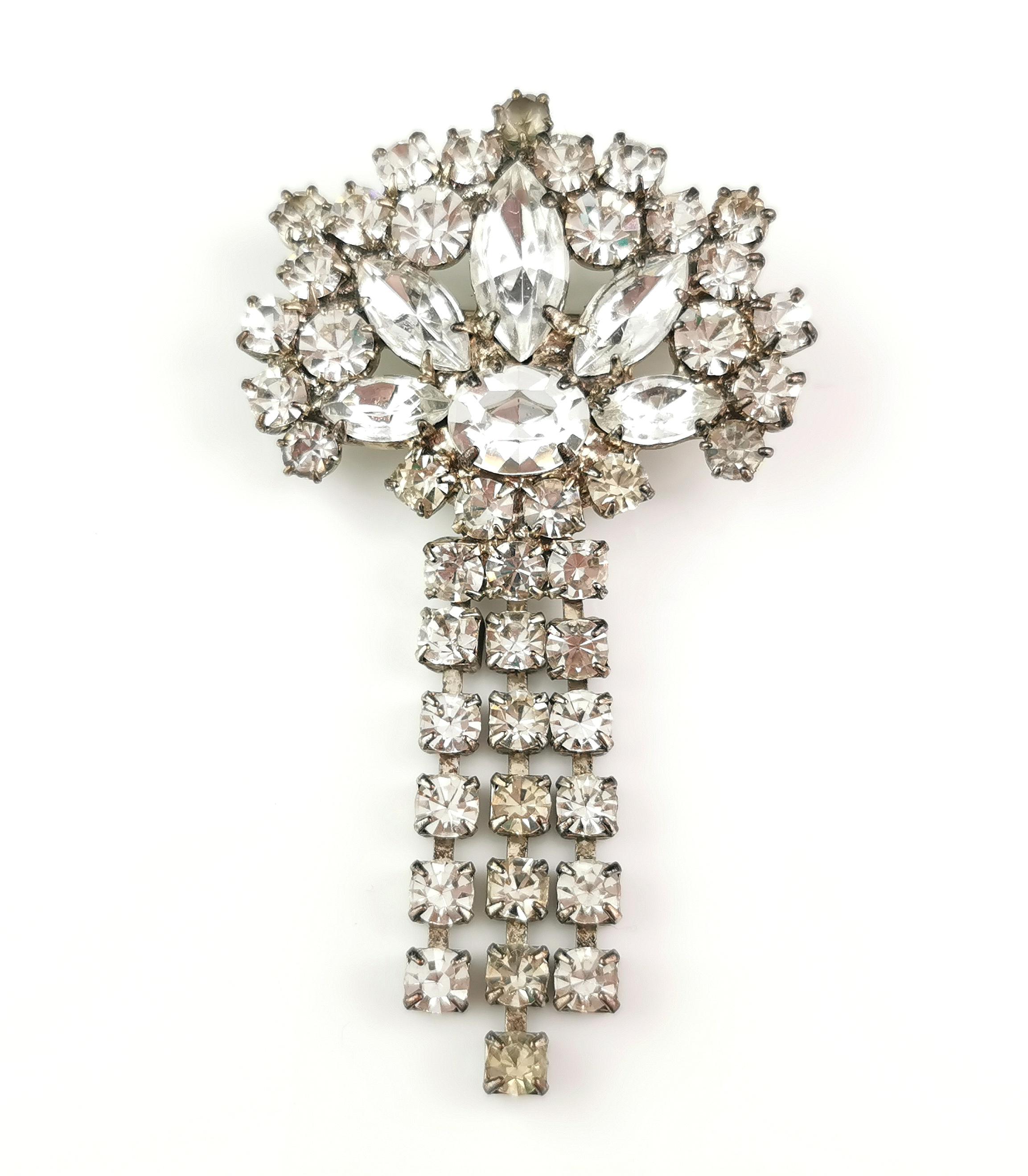 A gorgeous, sparkly vintage diamante dangle brooch.

Borrowing its style elements from the Art Deco era it has a fan style top set with different cuts of paste, it has a lovely tassel style drop, each of the tassels set with sparkling dismante.

The