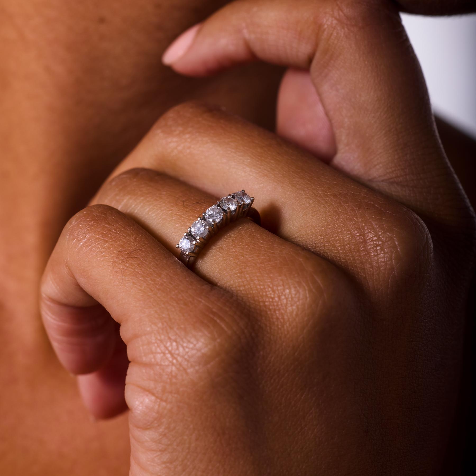 Elegante e senza tempo, questa fede vintage a cinque pietre degli anni '80 emana una raffinatezza classica. Cinque diamanti rotondi taglio brillante scintillano in armonia sulla fascia in oro bianco 14 carati, con un colore F-G e una chiarezza