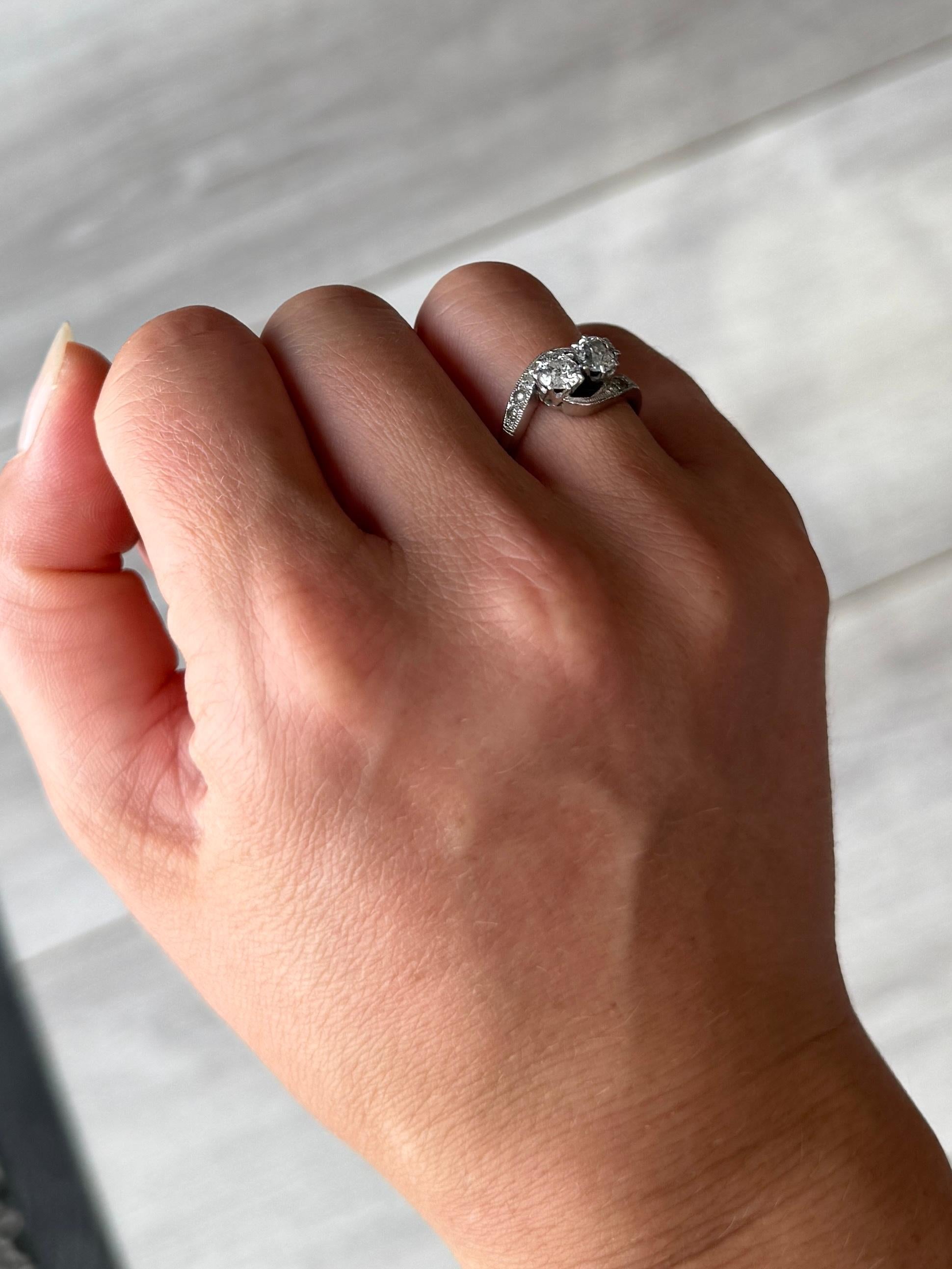 This elegant ring features two diamonds each measuring 40pts. The diamond shoulders total 7pts each side. This ring is modelled in 18 carat white gold and is a crossover design, also called Toi Et Moi / Moi Et Toi. 

Ring size : K 1/2 or 5 1/2