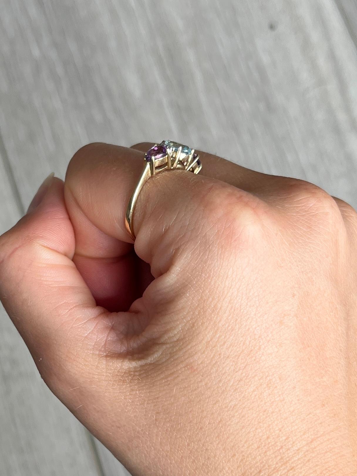 Die beiden lilafarbenen Amethyste haben zusammen ca. 60 Punkte und der Aqua-Stein 75 Punkte. Es gibt ein Paar von Diamanten auf beiden Seiten des zentralen Steins, die 8pts messen. Der Ring ist aus 9-karätigem Gold modelliert.

Ringgröße: P oder 7