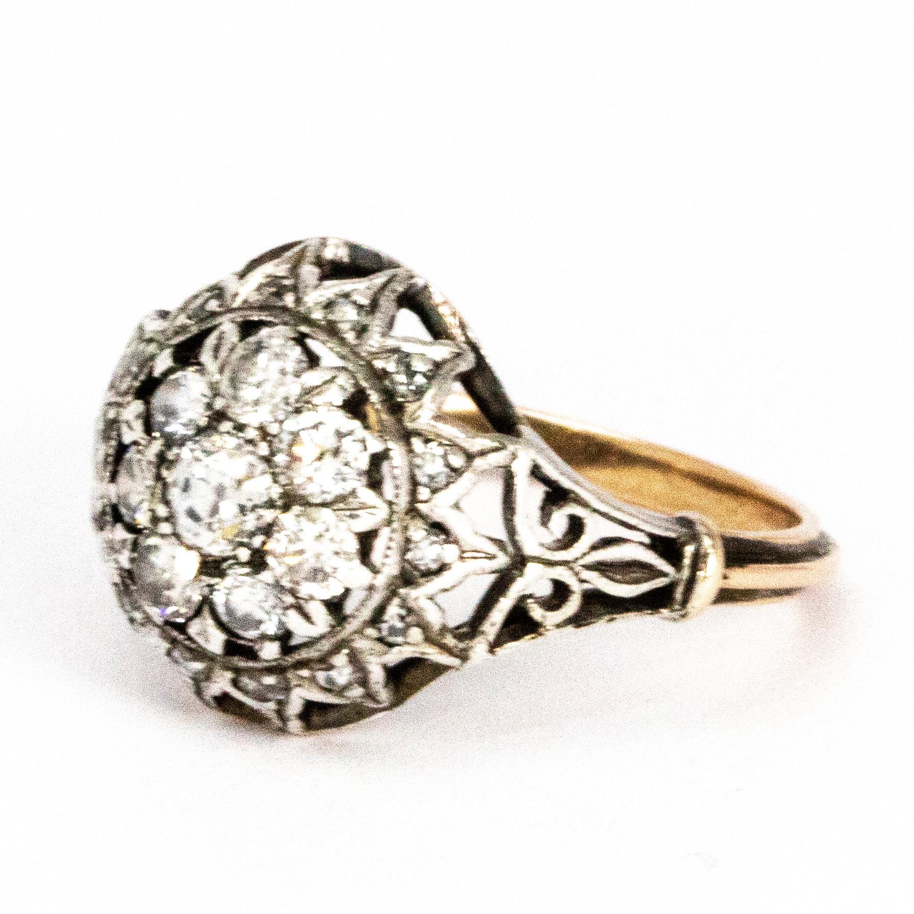 Das verschlungene Design dieses Rings ist einfach wunderschön. Er ist mit Diamanten verziert und aus 18-karätigem Gold modelliert. Der Mittelstein hat eine Größe von 20 Pence, die umliegenden Steine messen 7 Pence. Um den Cluster herum befinden sich