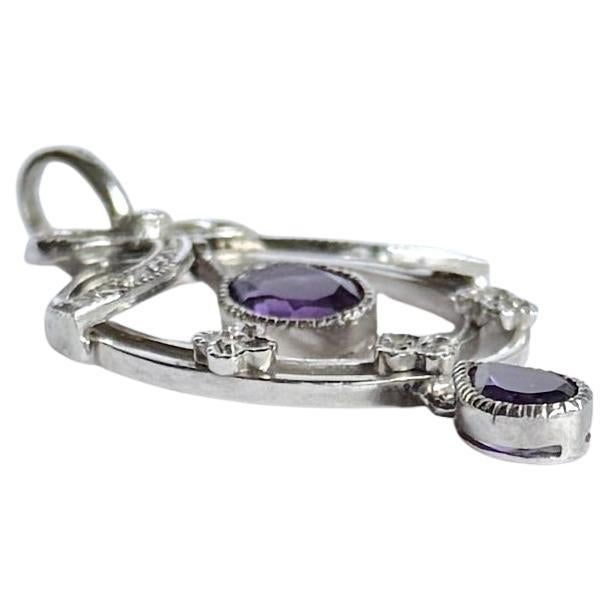 Dieser Anhänger ist aus 9 Karat Weißgold gefertigt und mit Diamanten und Amethysten besetzt. Die Gesamtzahl der Diamanten dieses Anhängers beträgt 20 Stück. Der Amethyst im Birnenschliff hat eine Größe von 40 pt und der ovale Amethyst von 70 pt.
