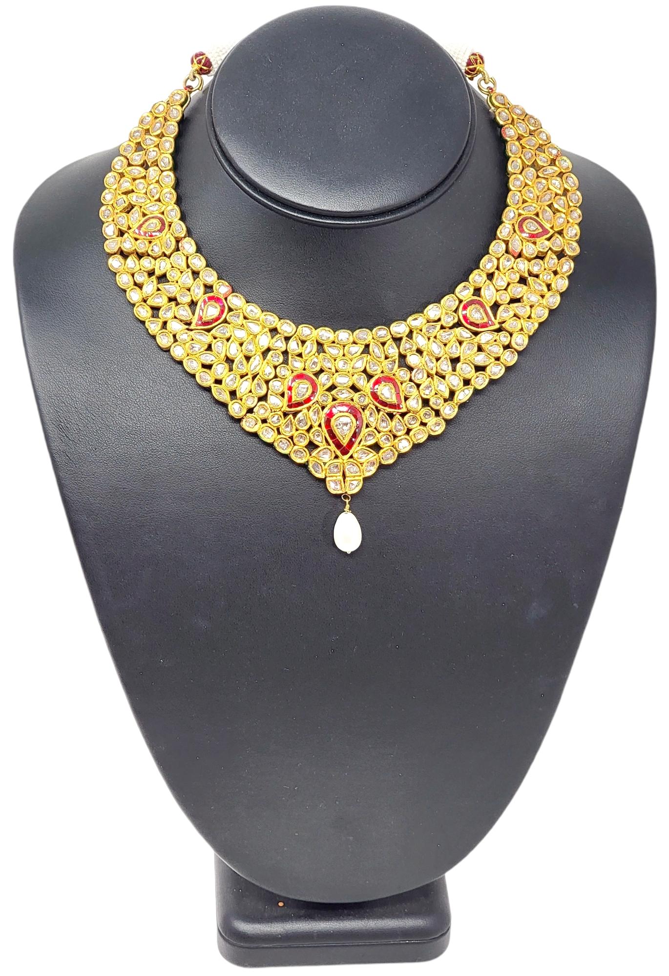 This spectacular, one-of-a-kind Polki necklace is absolutely gorgeous. Bursting with sparkling diamonds and rubies, this bib style necklace is sure to impress. The necklace features a unique cluster of uncut diamonds (H-J / SI) in varying shapes,