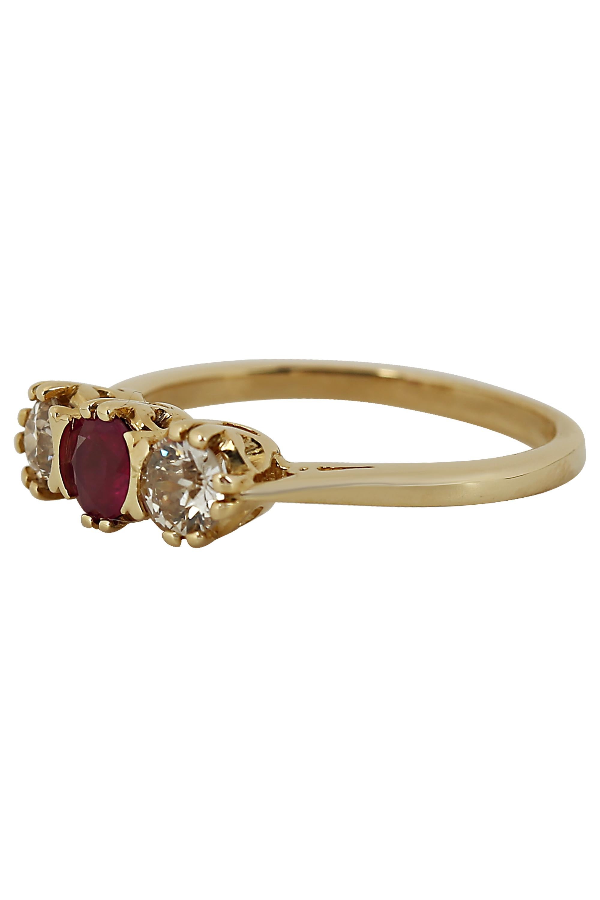A tailored three stone ring featuring a center ruby weighing approximately 0.35 carat illuminated by two European cut diamonds weighing approximately 0.40 carat total mounted in 14 karat yellow gold. Current size 6.75.


