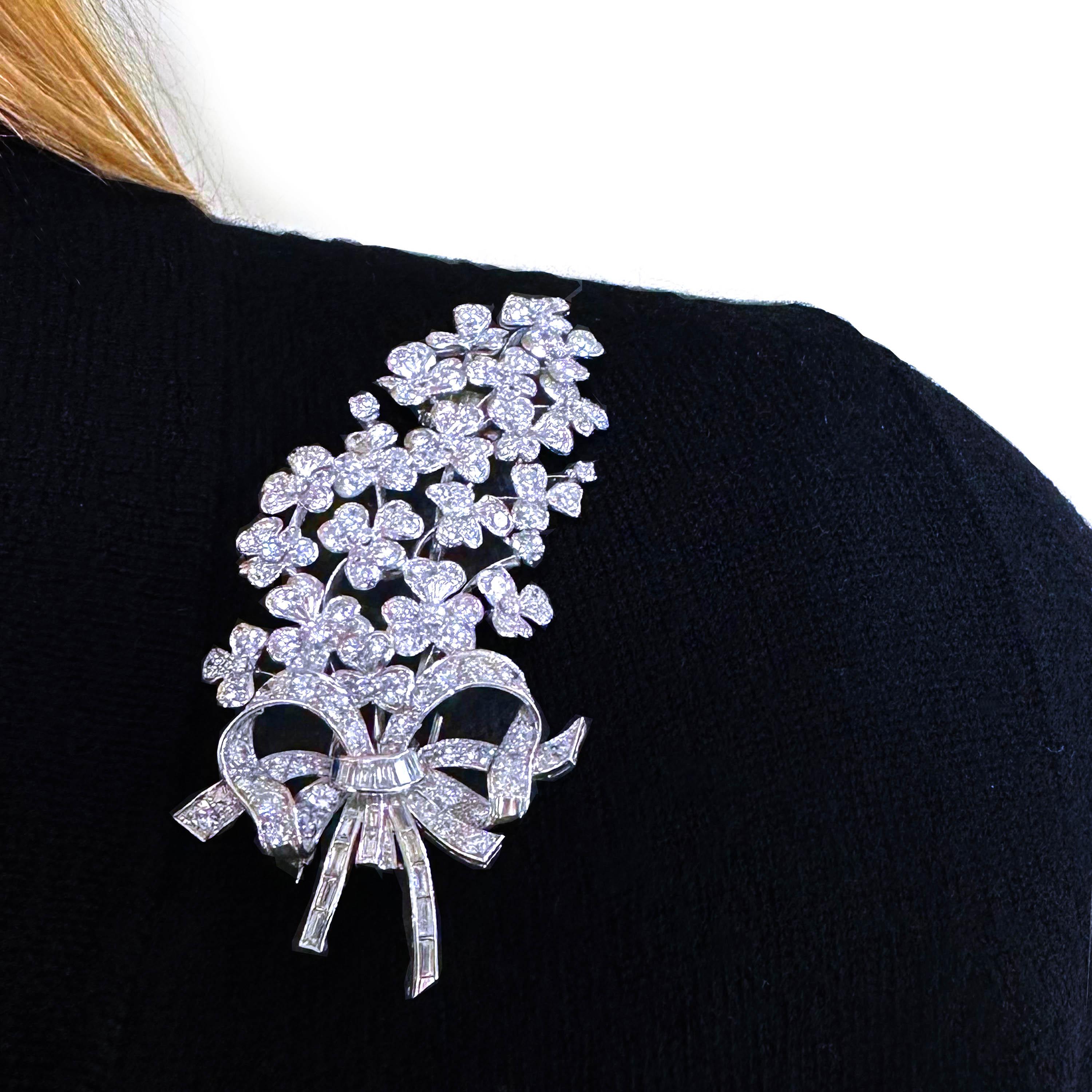 A vintage diamond flower brooch, in the form of a bunch of lilac, tied with a bow, set with round brilliant-cut diamonds in the blossoms and upper bow and baguette-cut diamonds in the lower bow and stems, mounted in white gold. Marked Made in