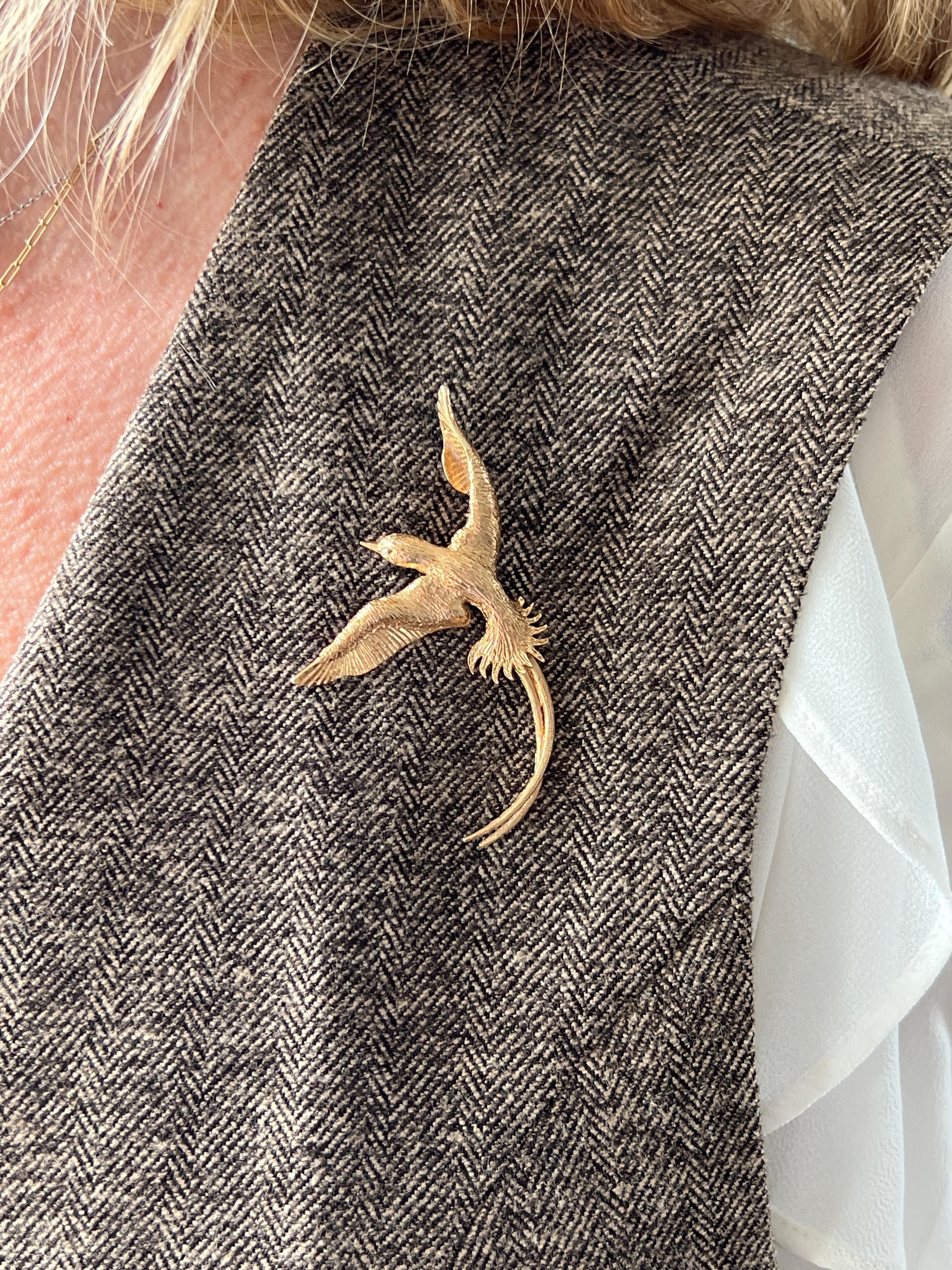 This vintage 14 karat yellow gold pheasant brooch captures the graceful form of a bird mid-flight with beautifully rendered detail. Set with a single cut diamond of approximately 0.01 carat for an eye,  the diamond adds a subtle sparkle,