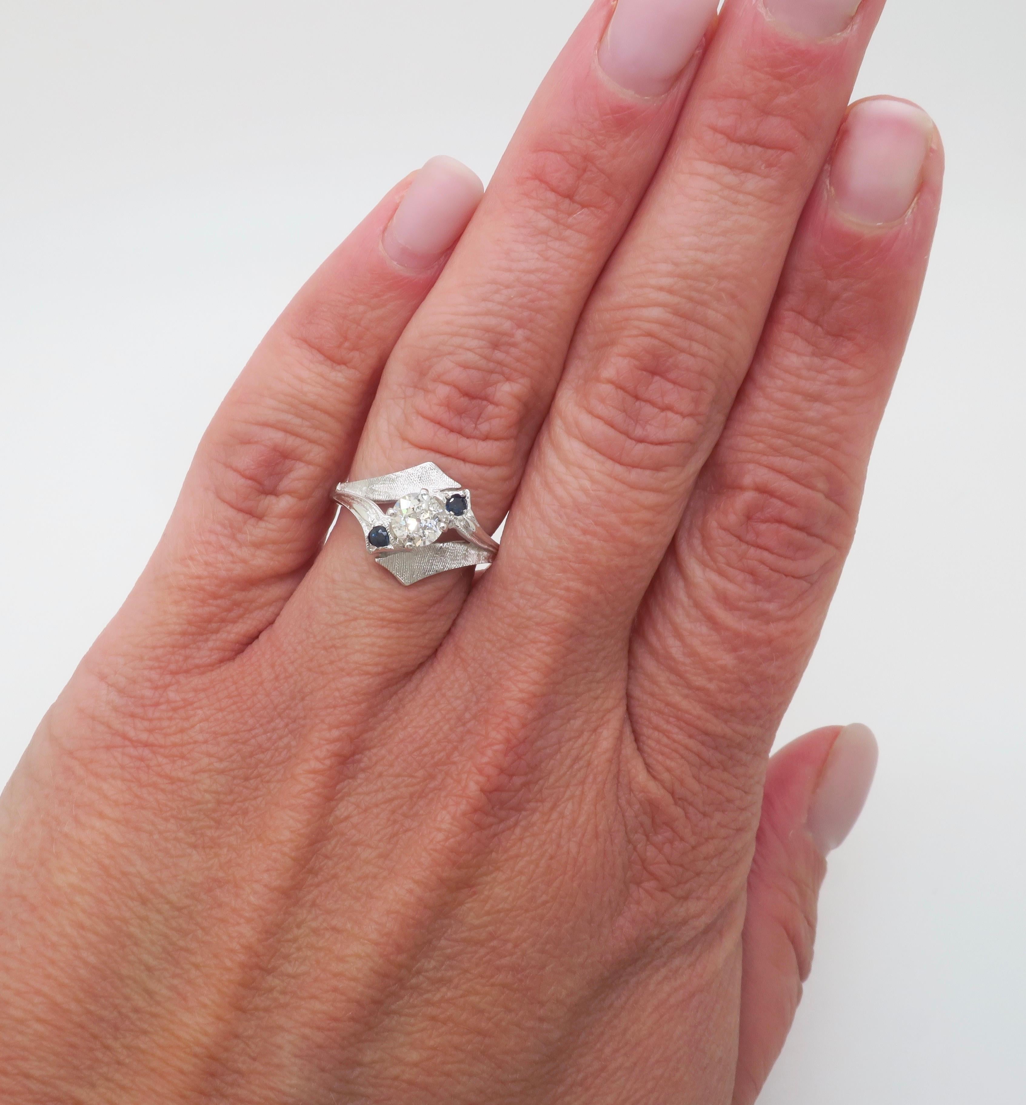 Bague bypass vintage en or blanc 14k sertie de diamants et rehaussée de saphirs bleus. 

Pierre précieuse : Diamant et saphir bleu extraits de la terre
Poids en carats du diamant central : .52CT
Taille du diamant central : Taille européenne ancienne