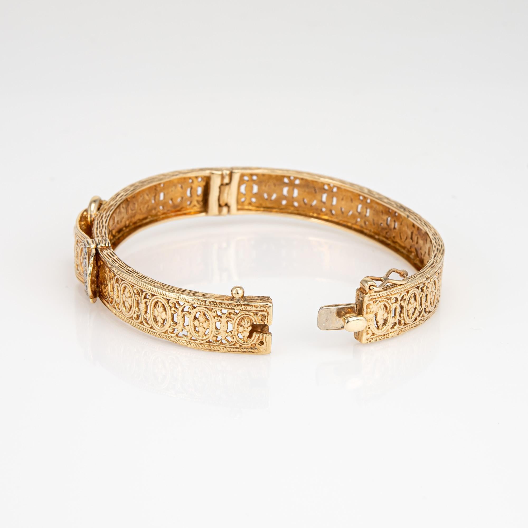 Stylish and finely detailed vintage buckle bracelet crafted in 14 karat yellow gold. 

Four diamonds total an estimated 0.08 carats 9estimated at H-I color and VS2-SI1 clarity). 

The bangle features an elaborate design of scrolled and paneled