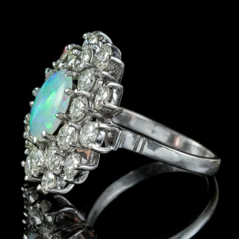 A magnificent vintage cluster ring from the mid 20th Century adorned with a colourful, natural opal in the centre weighing approx. 3ct, surrounded by a burst of twenty dazzling brilliant cut diamonds with excellent clarity and colour (approx. 0.18ct