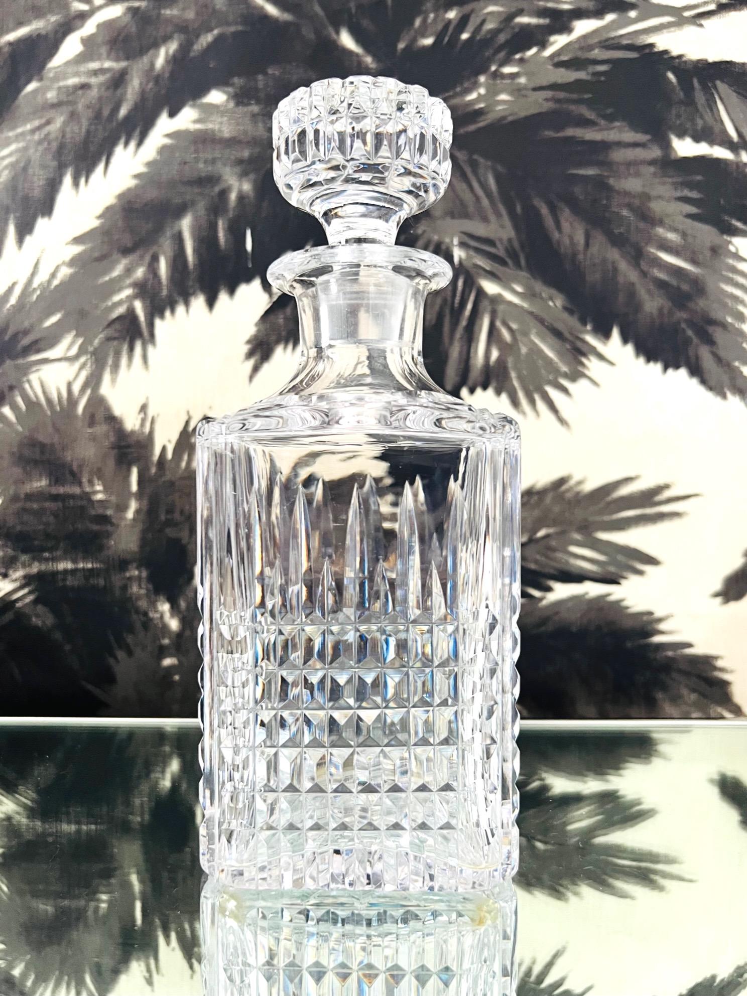 Vintage Waterford Crystal whiskey decanter with diamond cut pattern throughout. The decanter has a square form a stylized flat top stopper. Features an etched starburst on the underside has cross hatched patterns along the stem and top of the