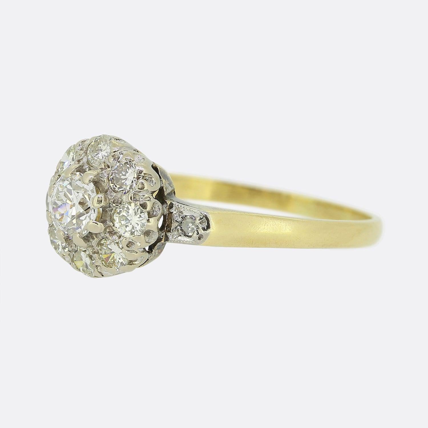 Here we have a classic diamond cluster ring. A single round faceted old European cut diamond sits slightly risen at the centre of the face and is framed by a circulating array of brilliant cut diamonds. All stones here are set in platinum with a