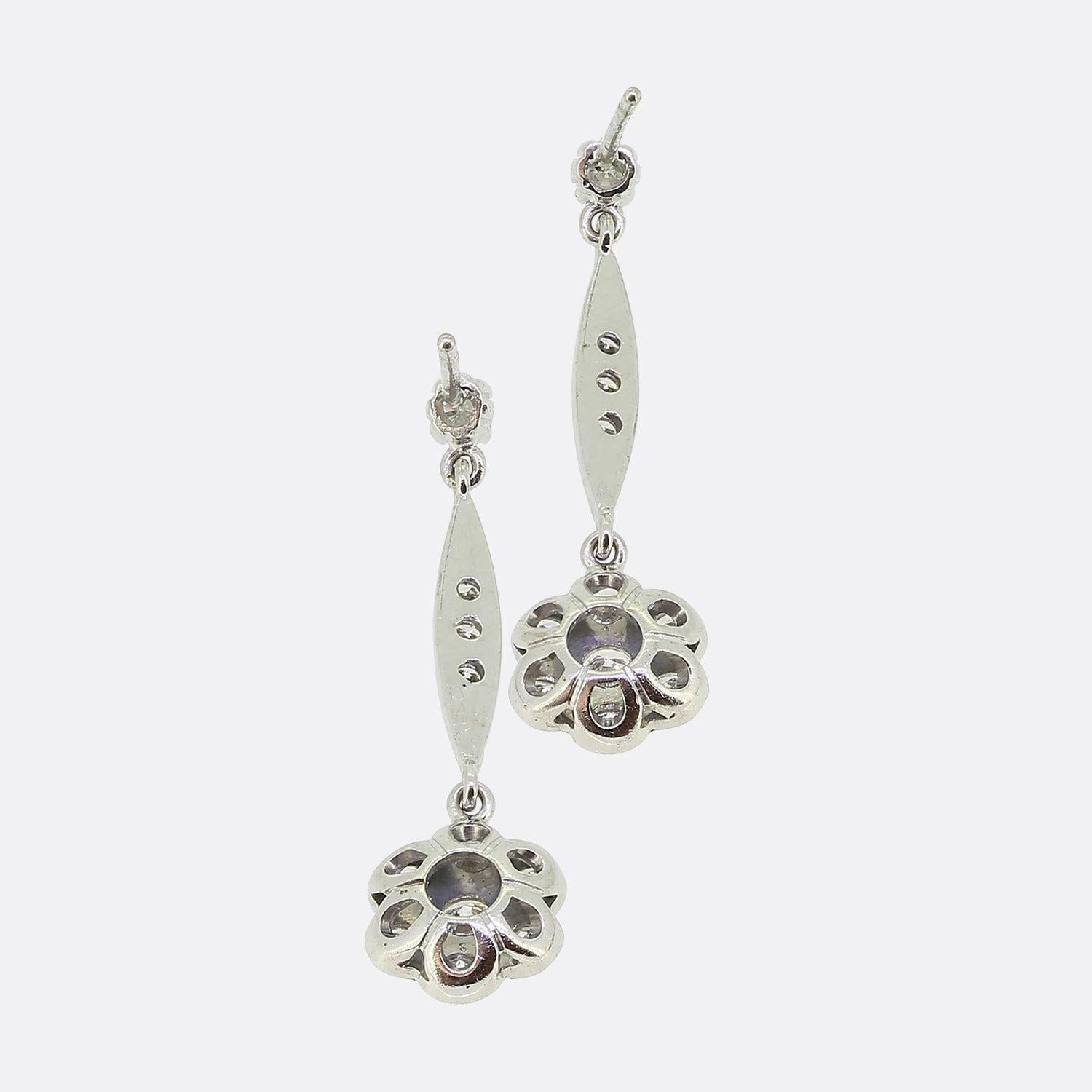Here we have a wonderful pair of 18ct white gold diamond drop earrings. Each vintage piece showcases a single claw set round brilliant cut diamond at the very top. This lone stone plays host to diamond set bar below consisting of three matching