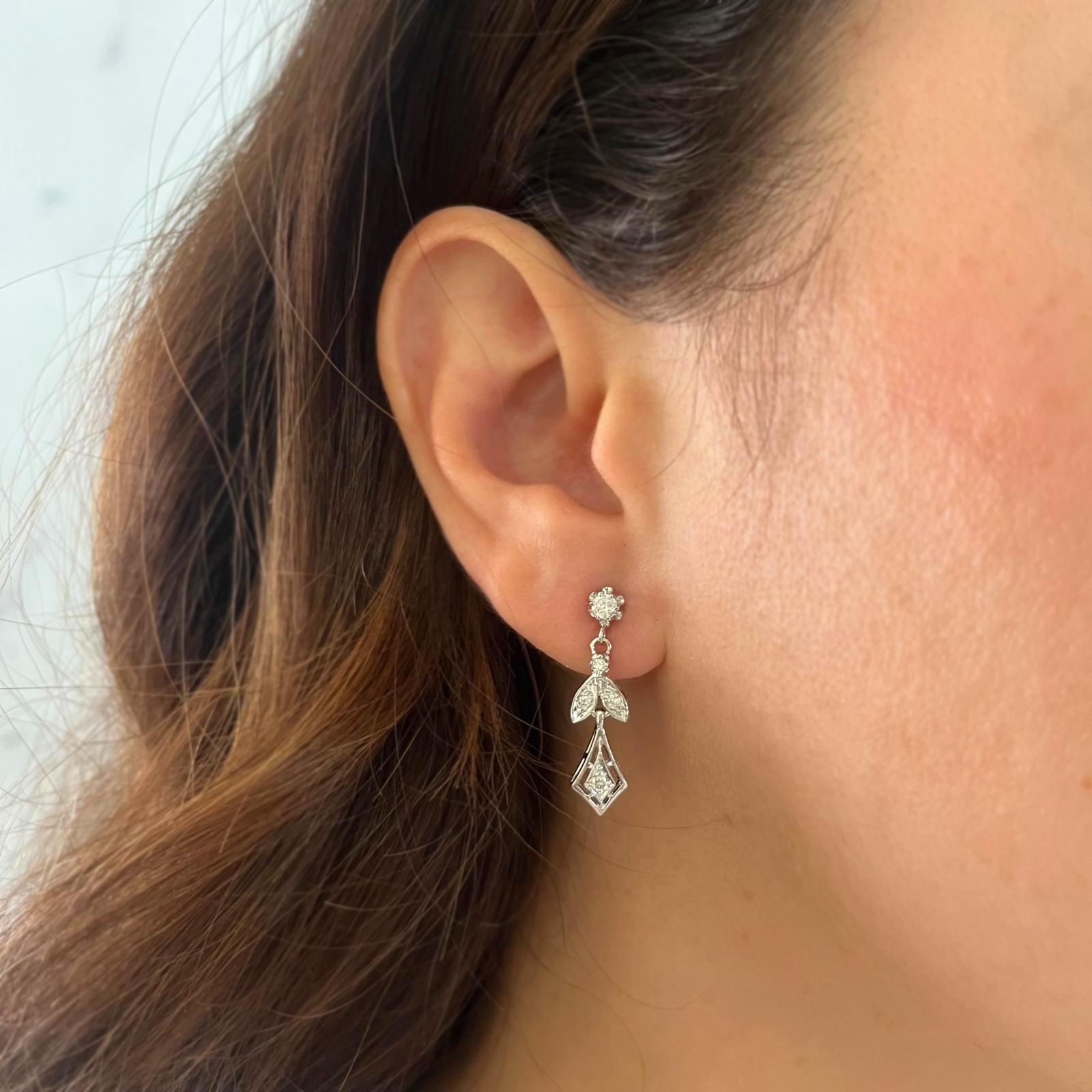 14 Karat White Gold Vintage Drop Earrings Featuring 10 Round Brilliant Cut Diamonds of SI Clarity and H Color Totaling 0.25 Carats. Pierced Post with Friction Back. 1.1 Inches Long. Finished Weight is 3.7 Grams.