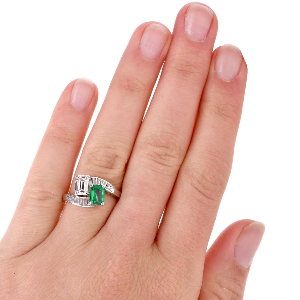 This classic vintage diamond and emerald bypass ring is crafted in solid platinum. Centered by an emerald cut emerald with natural inclusions approx. 0.95 carats and an emerald cut diamond approx. 0.80 carats, G-H color, VS clarity. Displaying a