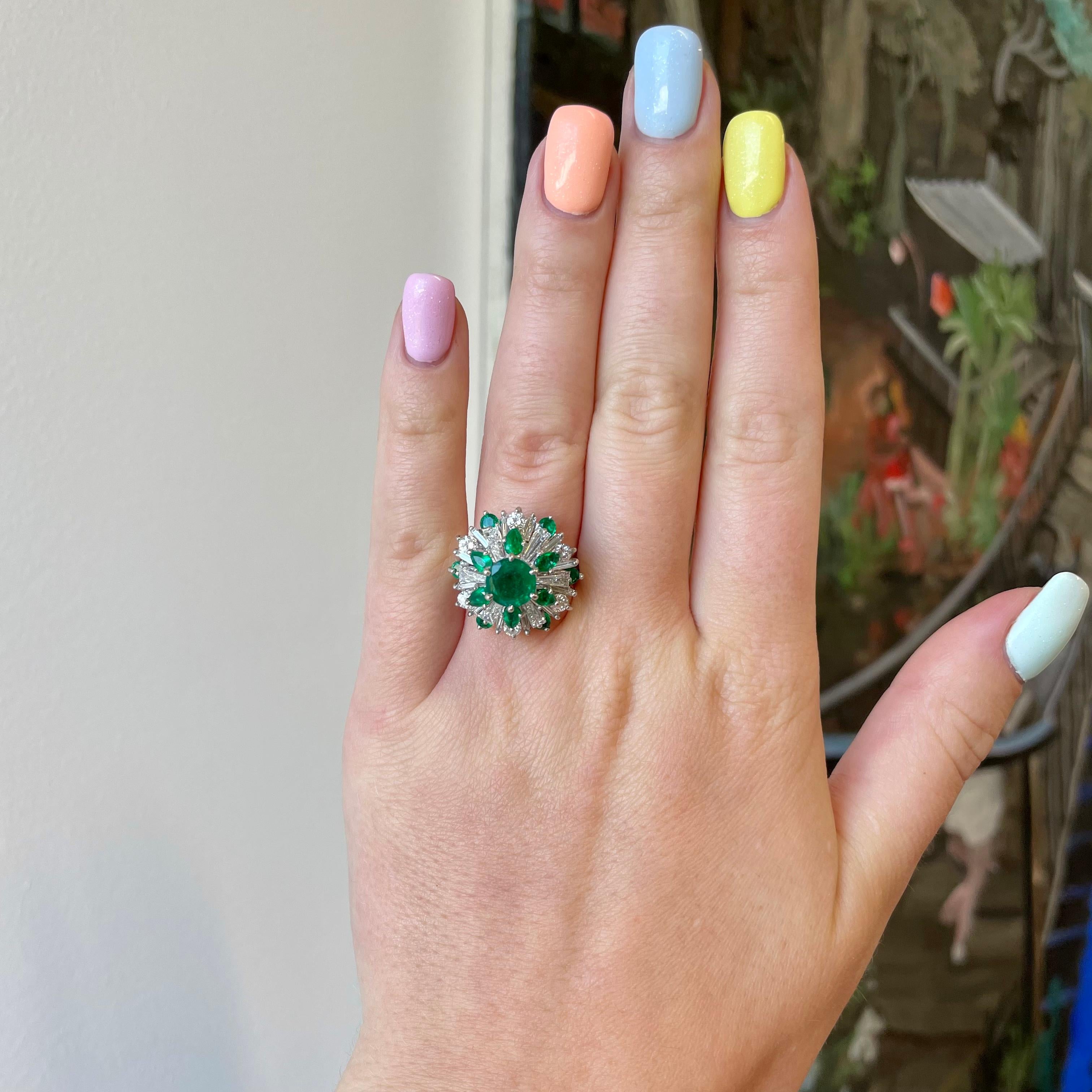 Vintage Diamond Emerald Platinum Cocktail Ring. The ring features a round emerald approximately 1.10 carat. Accompanied by 6 marquise, 6 round emeralds approximately 1.02 carat. As well as 6 tapered baguettes, 6 Round Brilliant and 12 baguette cut