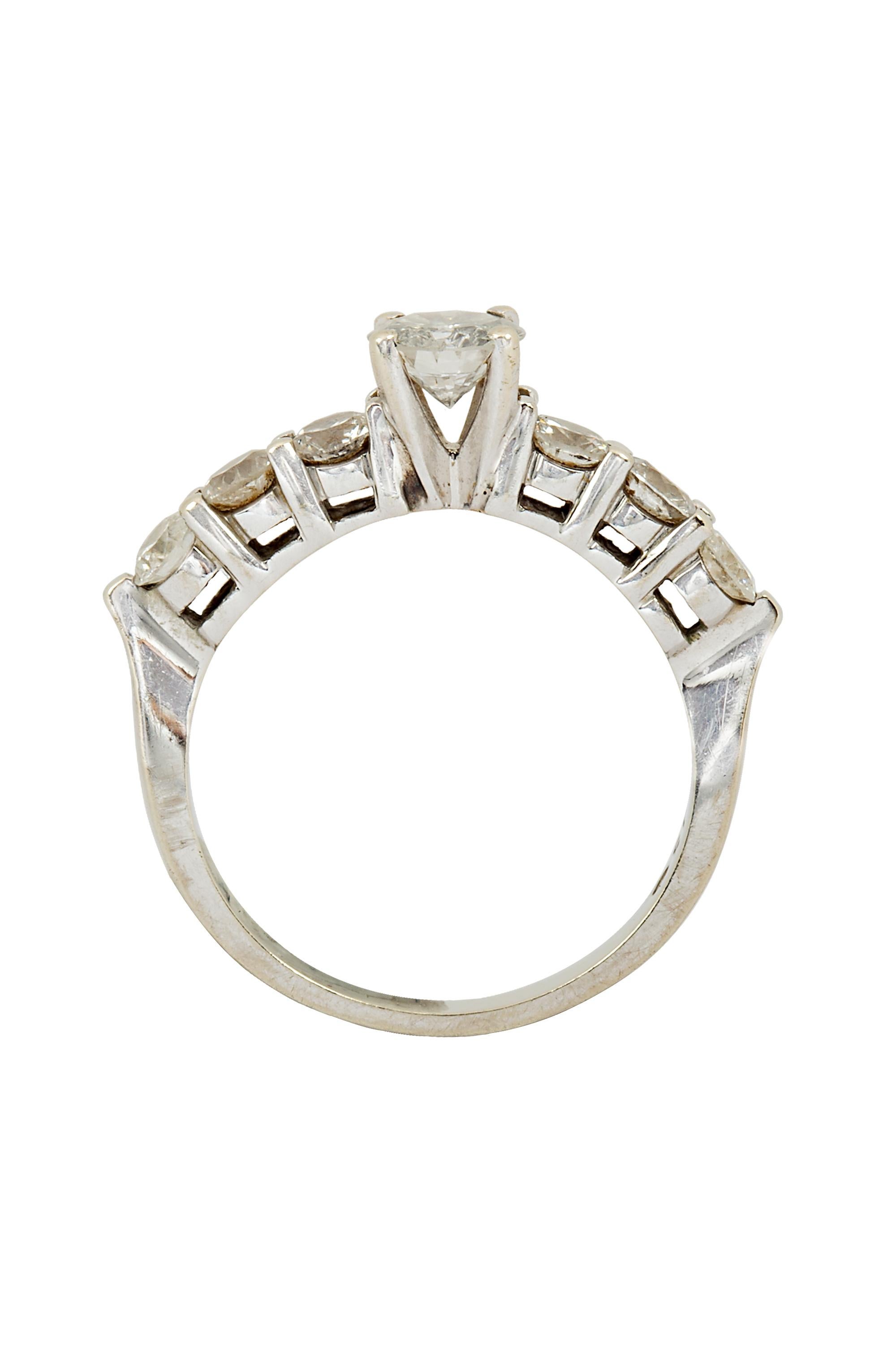 Classic diamond engagement ring with round brilliant cut at center, weighing approximately 0.60 carat, H color and I clarity. The center diamond is set in prongs, accented with 6 side stones weighing approximately 0.90 ctw.  The ring is crafted in