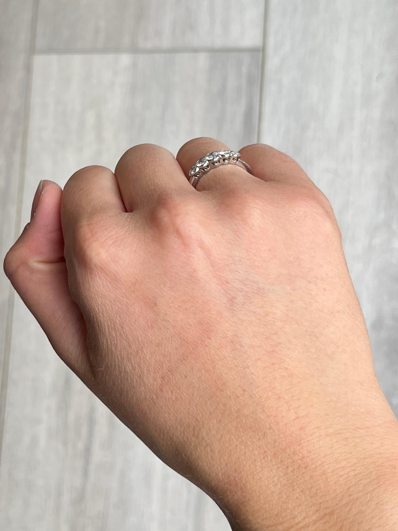 An exquisite vintage five-stone diamond ring, modelled in platinum. Set with five impressive graduated white diamonds on fine rub over settings, G colour VVSI clarity. The central stone measures 25 points and is flanked either side by 15 point
